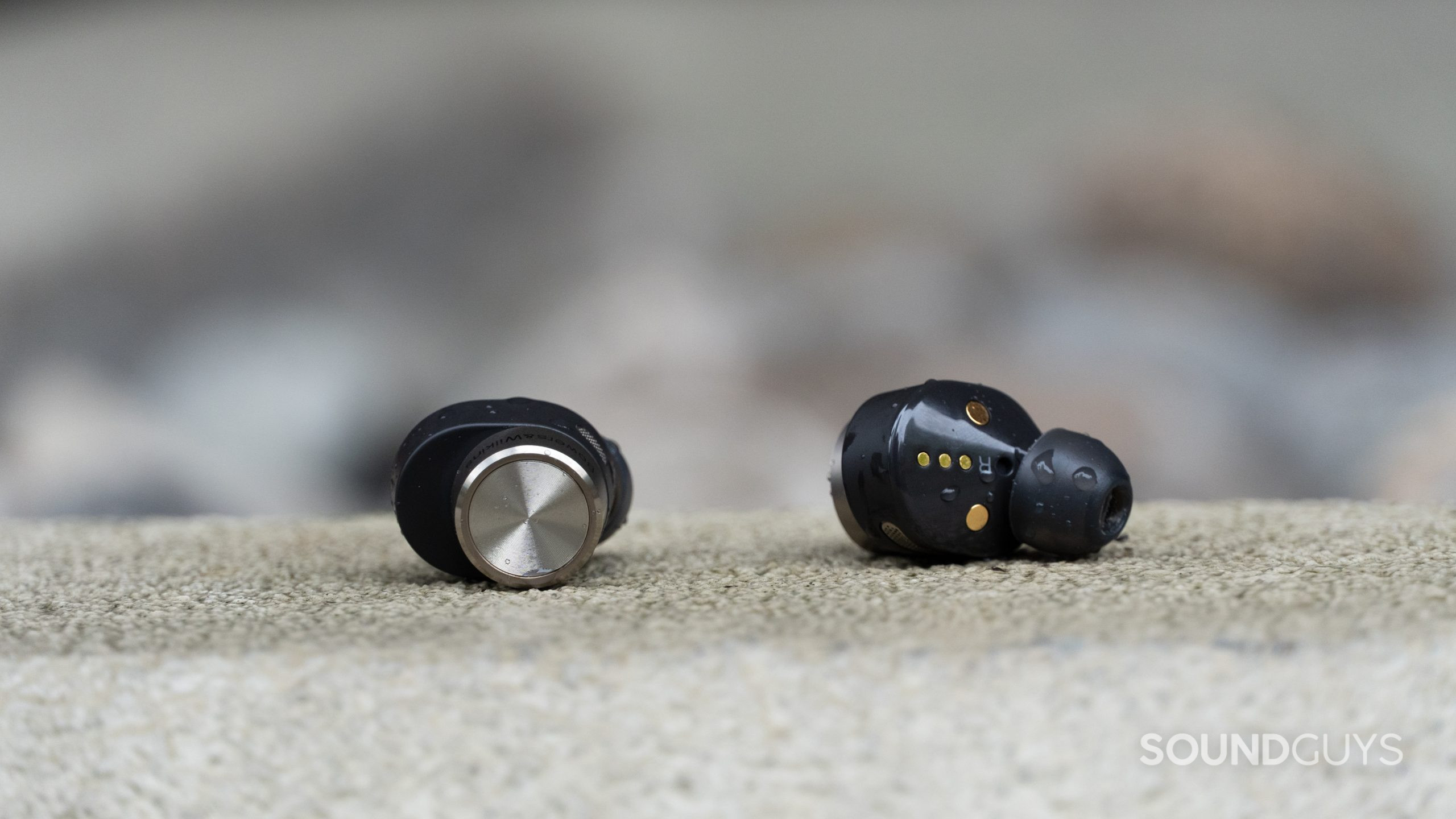 Bowers and Wilkins PI7 earbuds covered in drops of water.