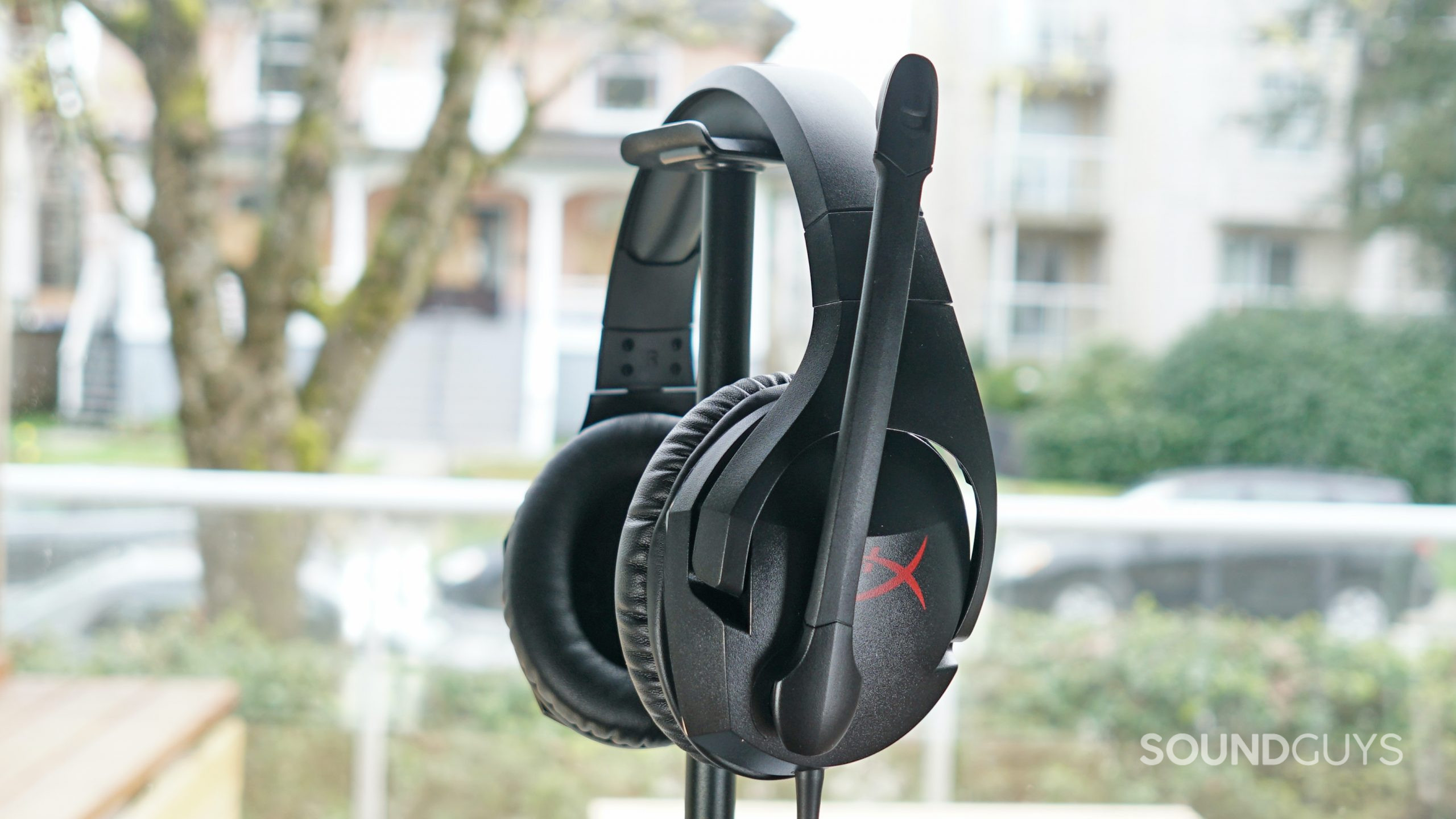 The HyperX Cloud Stinger sits on a headphone stand in front of a window.