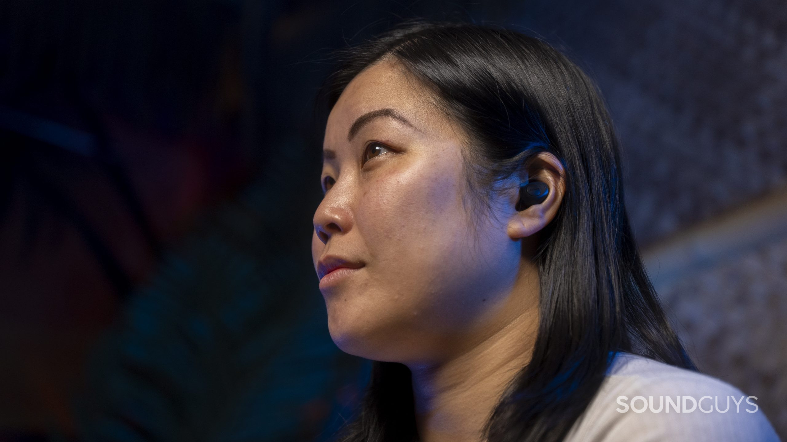 A woman wears the Jabra Enhance Plus hearing aid hearable.