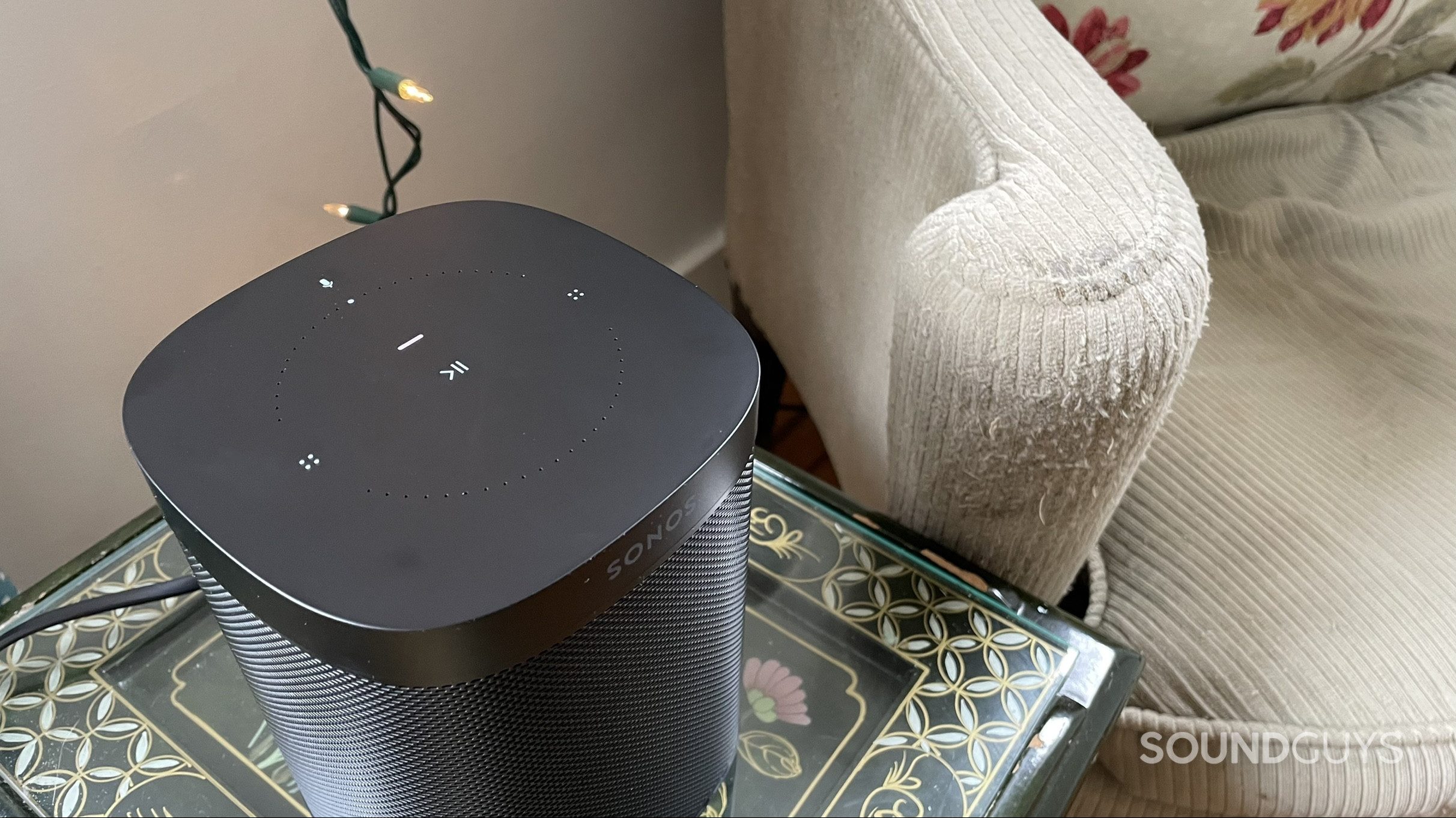 Top of Sonos One Gen 2 on a side table displaying its touch controls.