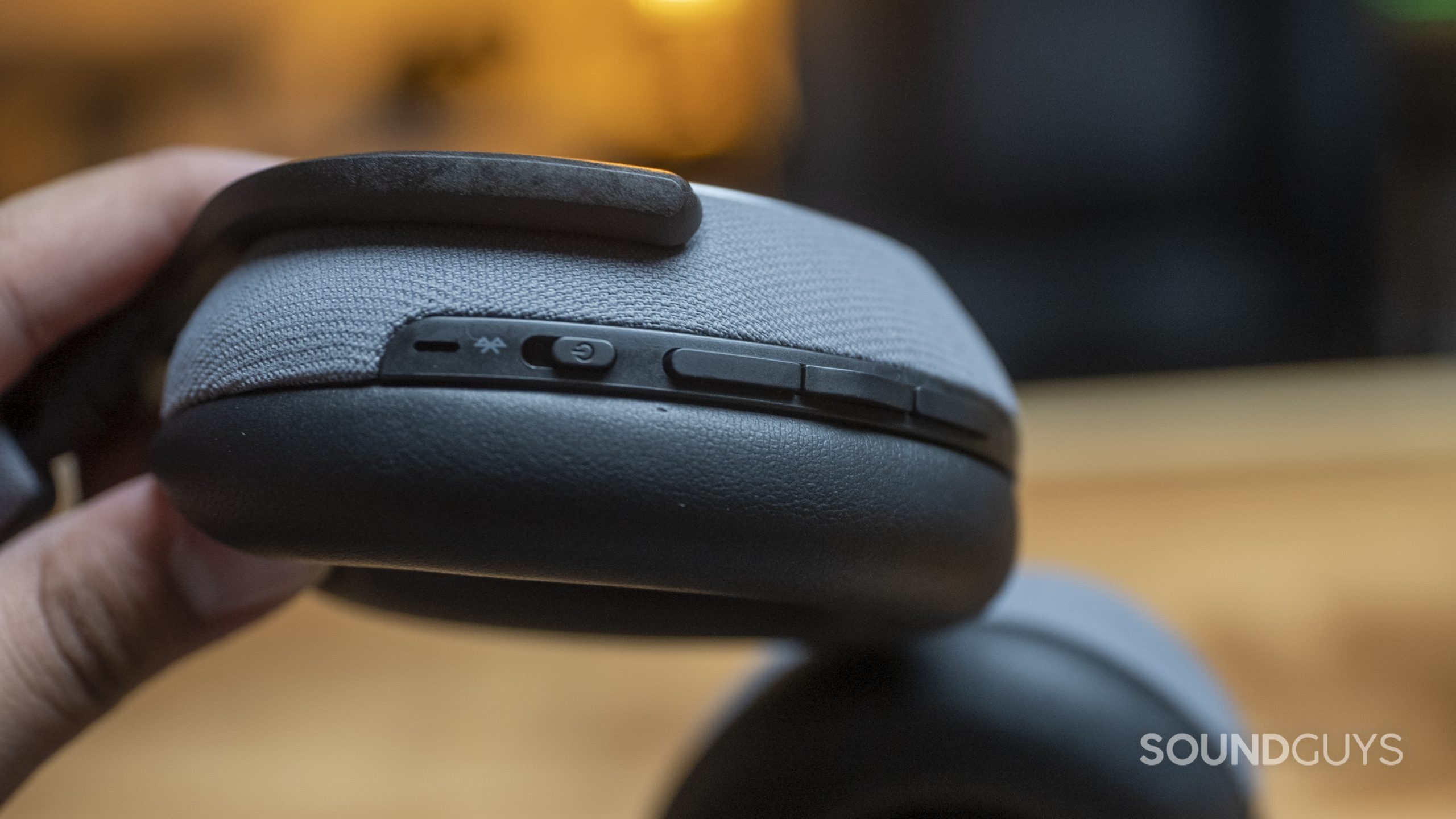 A hand holds the Bowers &amp; Wilkins PX7, showing off the controls on the right ear cup.