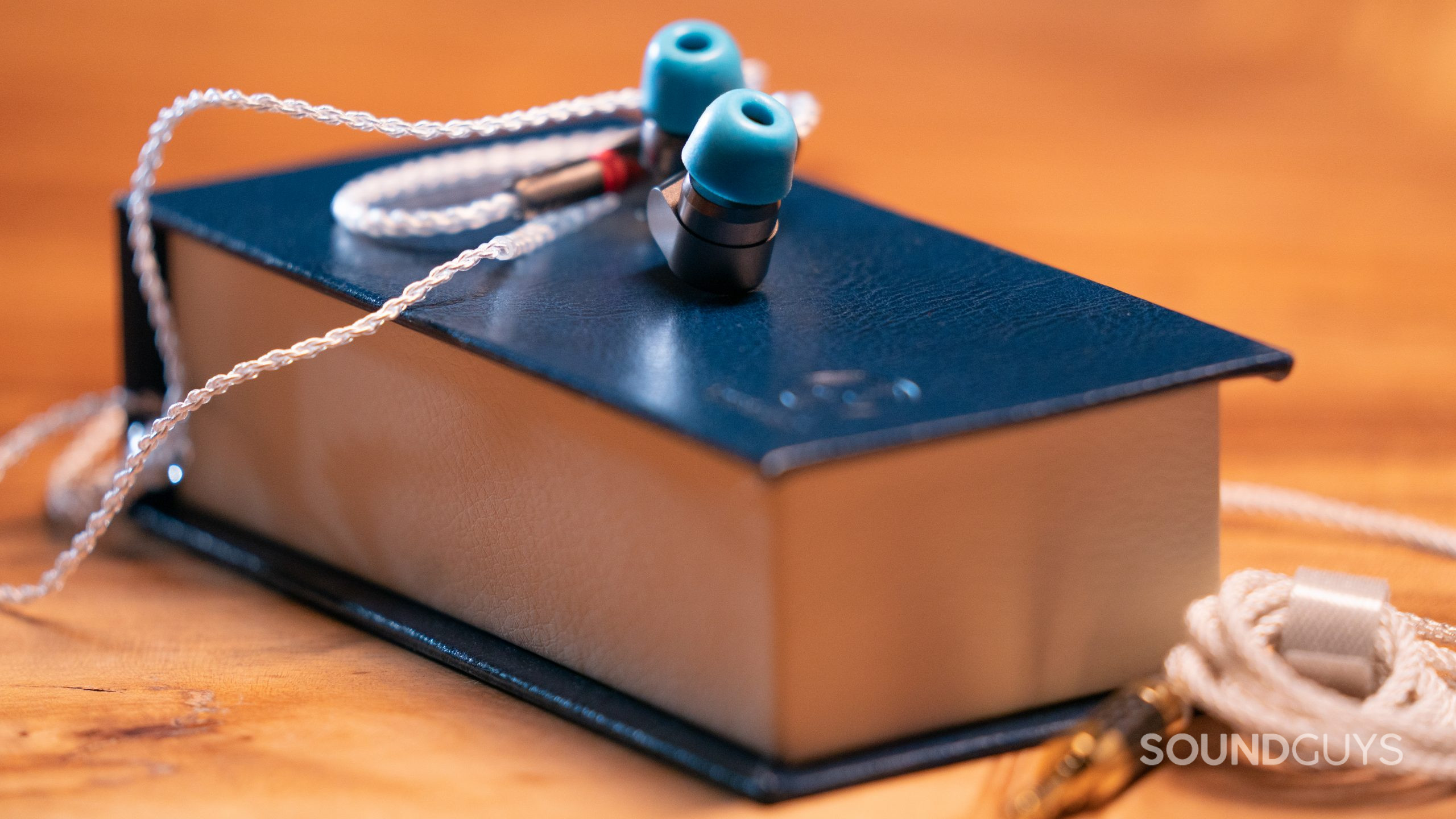 The Linsoul TIN Audio sits on the navy box with the cable in the foreground.