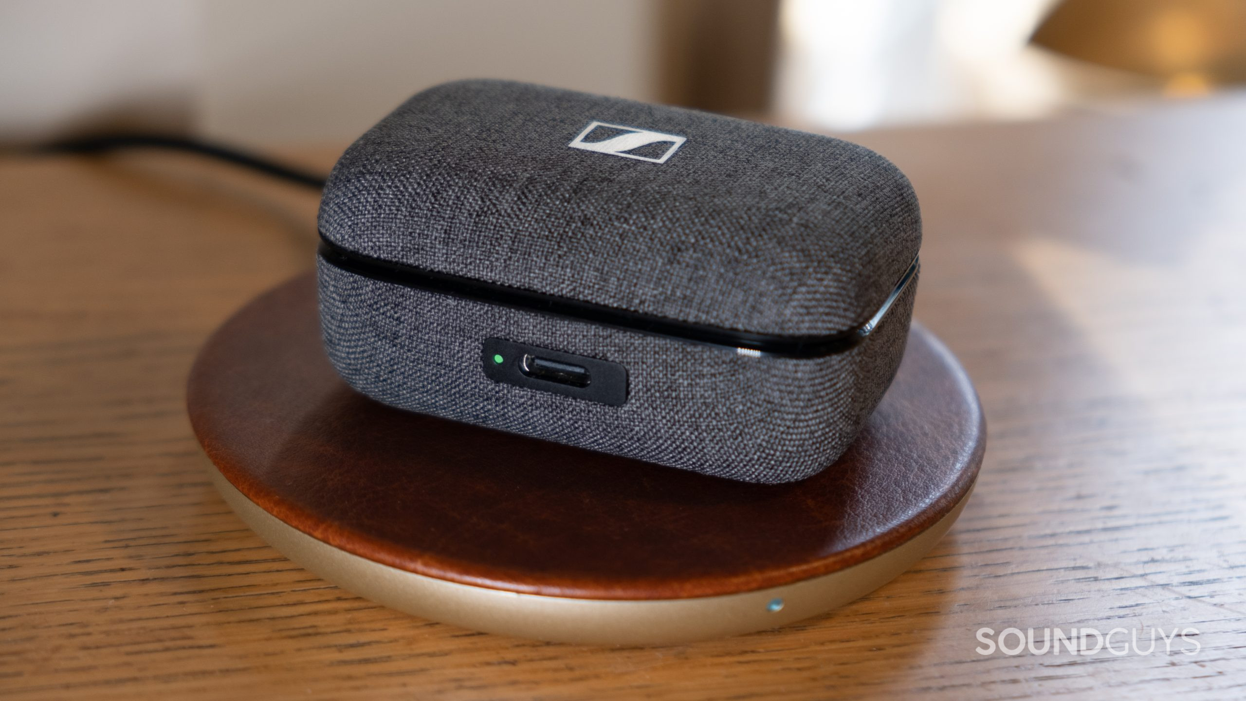The closed battery case for the Sennheiser MOMENTUM True Wireless 3 charges on a wireless charging pad.