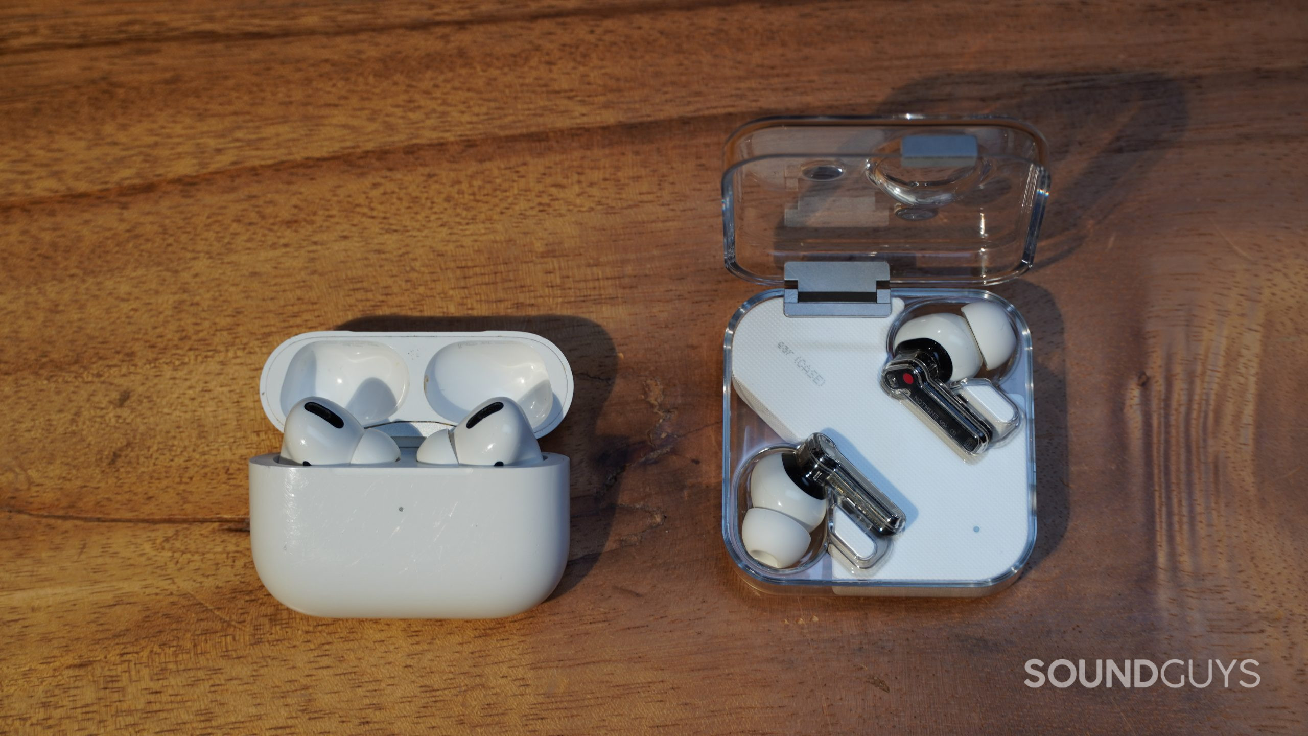 Apple AirPods Pro next to Nothing Ear 1 on a wood table