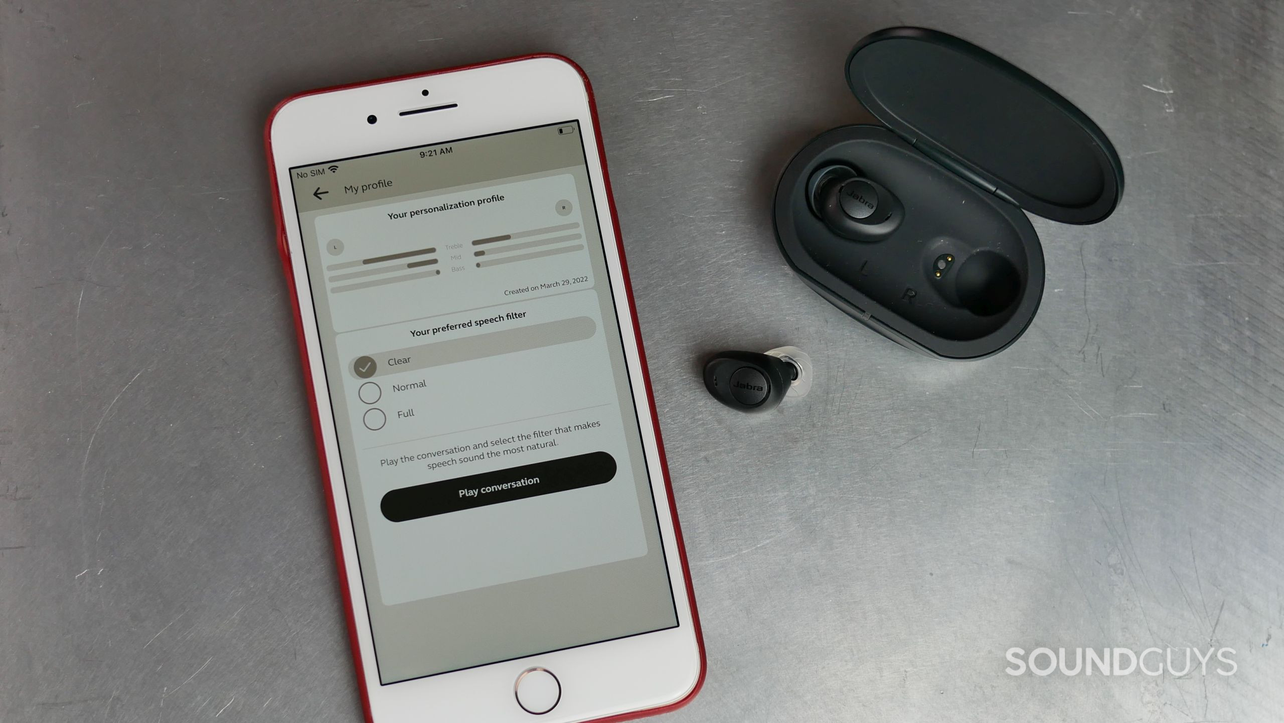 Jabra Enhance Plus earbuds and charging case with iPhone and Jabra Enhance app on personalization screen.