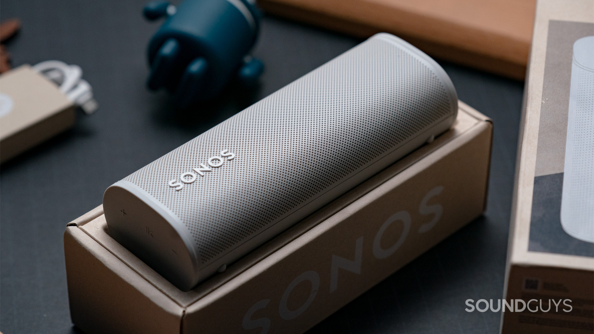 A white Sonos Roam speaker sitting face-up inside of the box it came in.