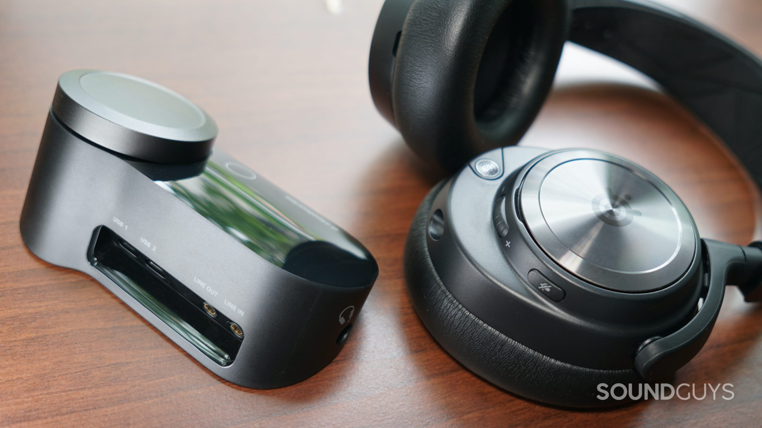 The SteelSeries Arctis Nova Pro lays on a wooden surface near the GameDAC unit.