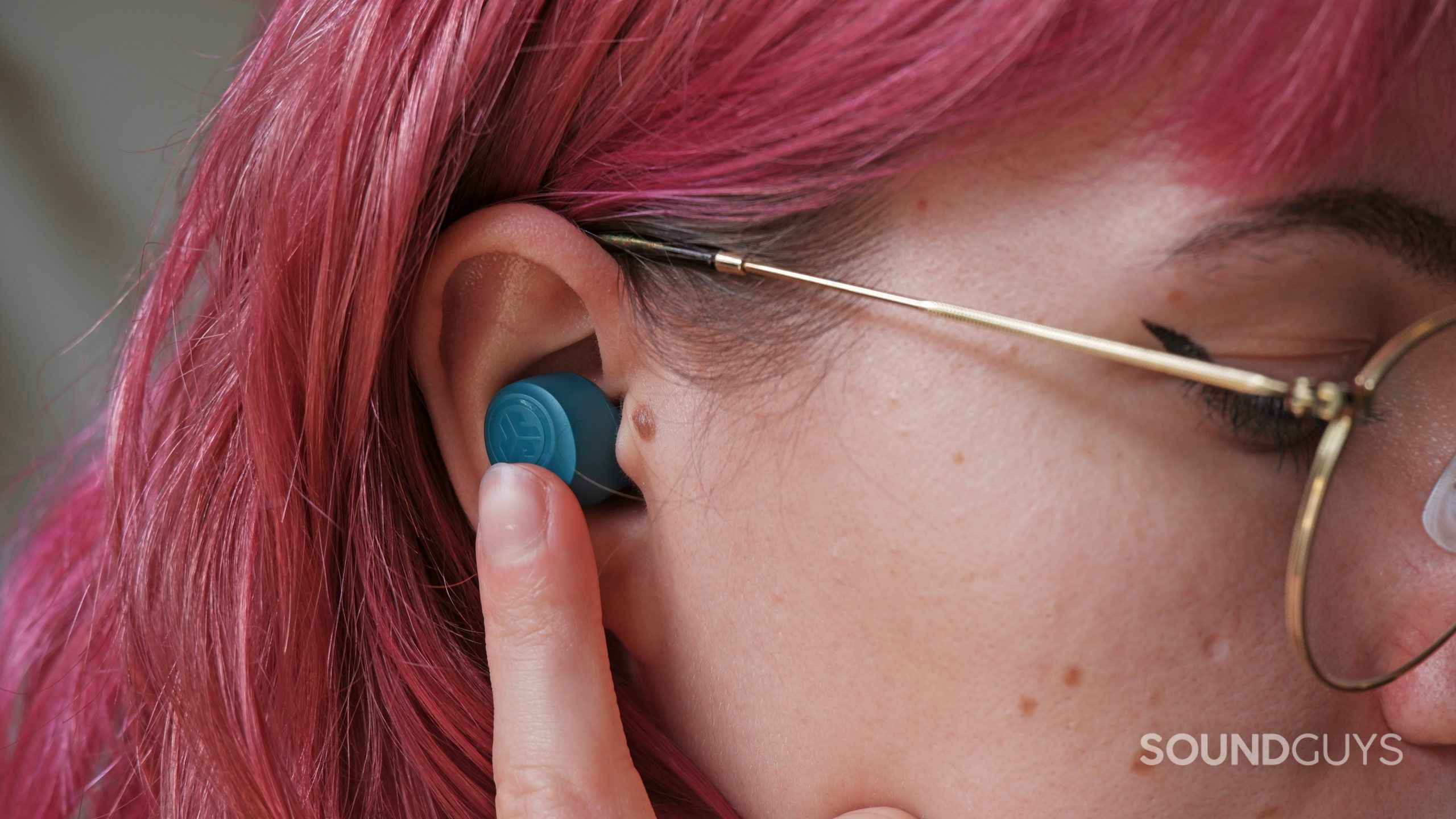 The JLab GO Air POP inside an ear, with a finger on the touch panel.