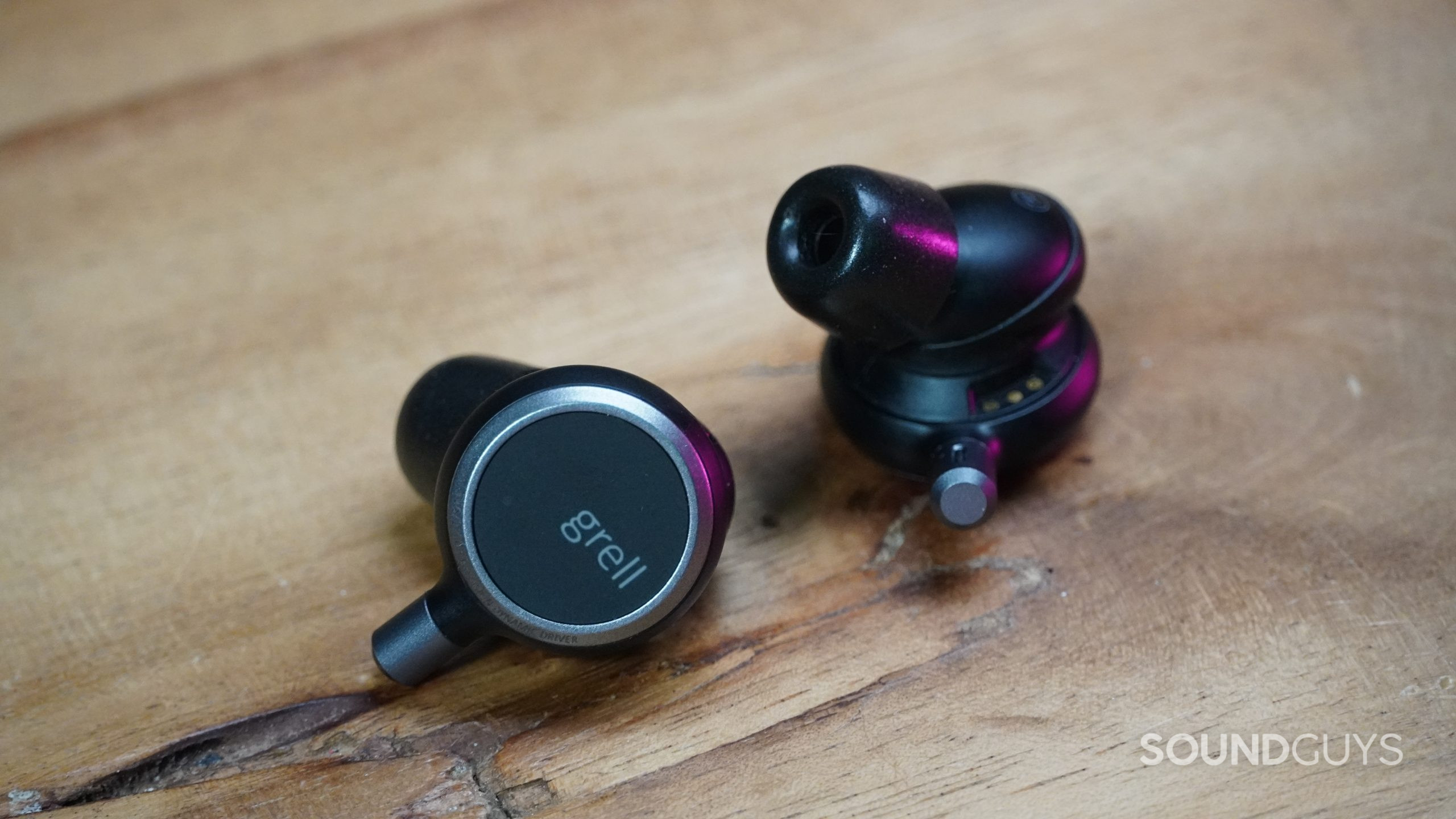 Grell Audio TWS 1 earbuds laying on a wood table