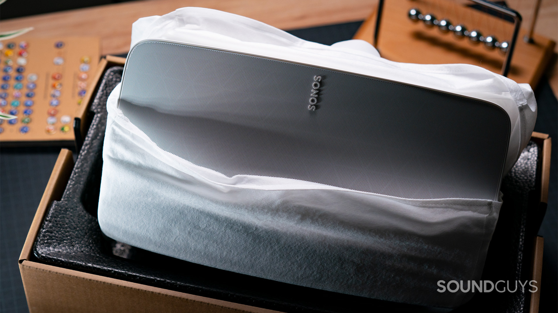 A white Sonos Five speaker in its box partially removed from its white protective fabric bag.