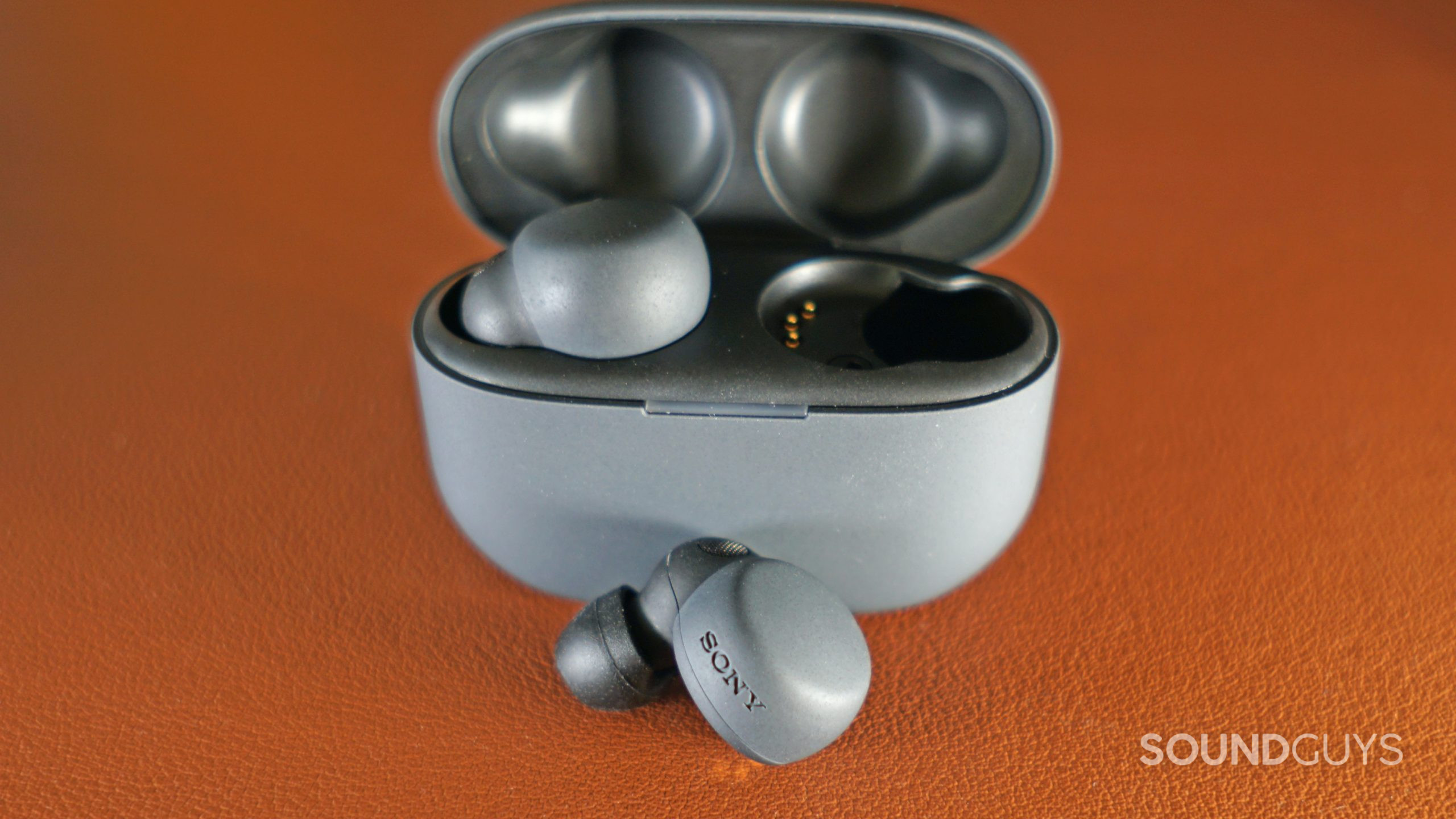 The Sony LinkBuds S sits on a leather surface with one earbud out.