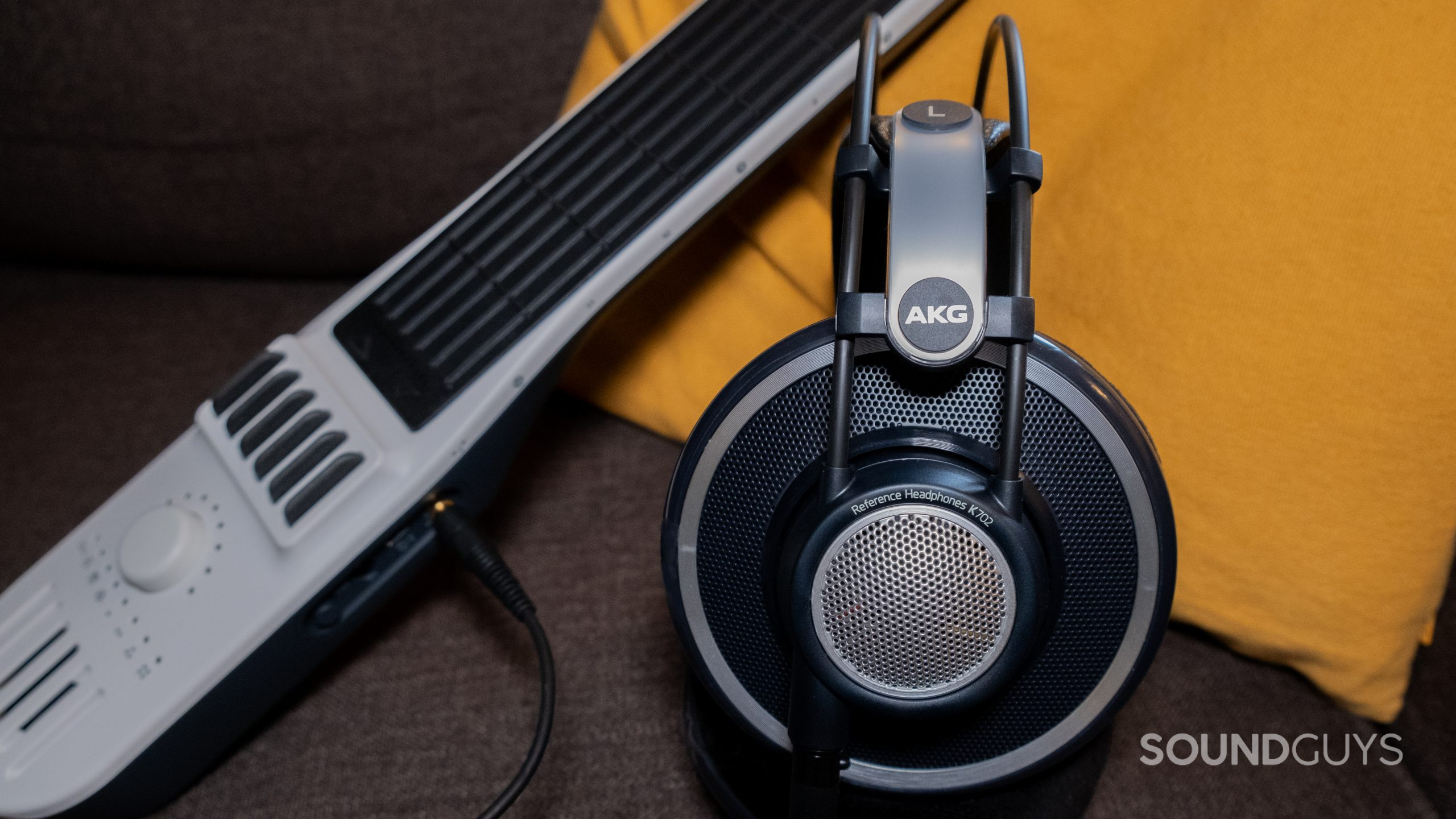 The AKG K702 rests against a yellow pillow next to a midi controller, shown from the side.