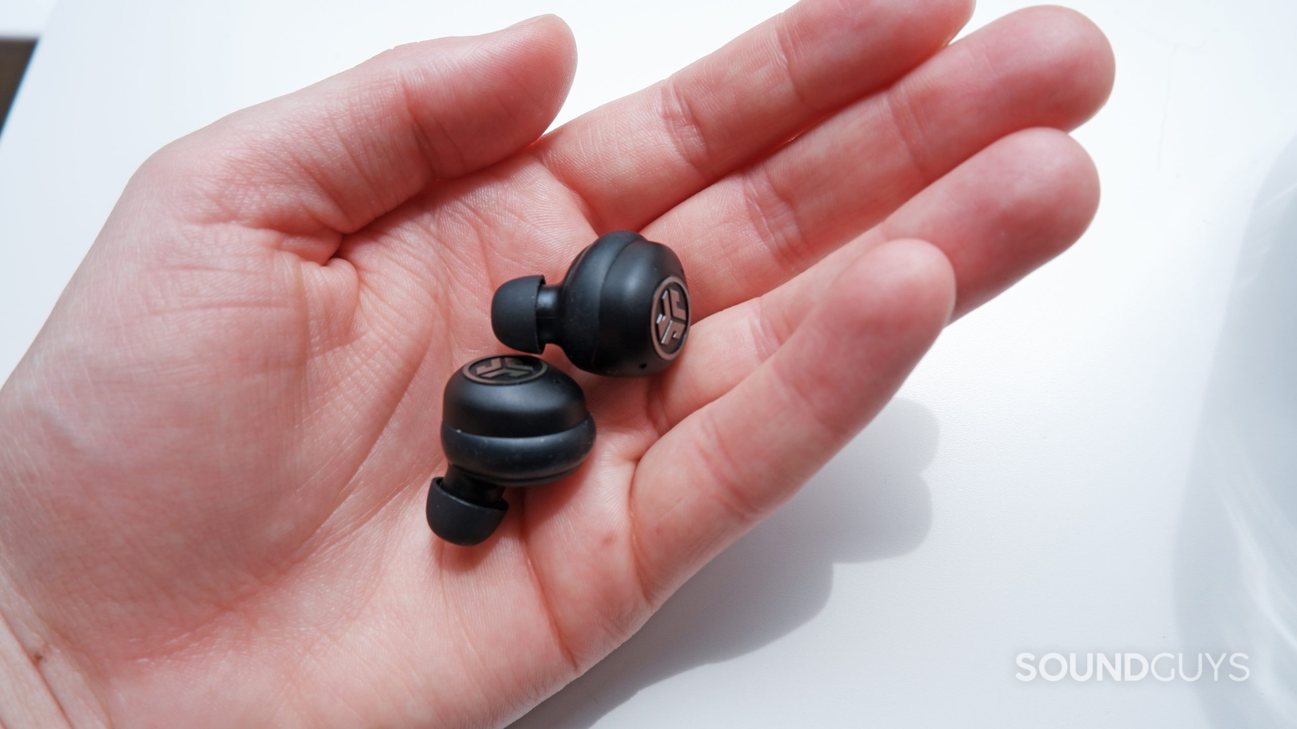 JLab JBuds Air Pro earbuds in a hand.