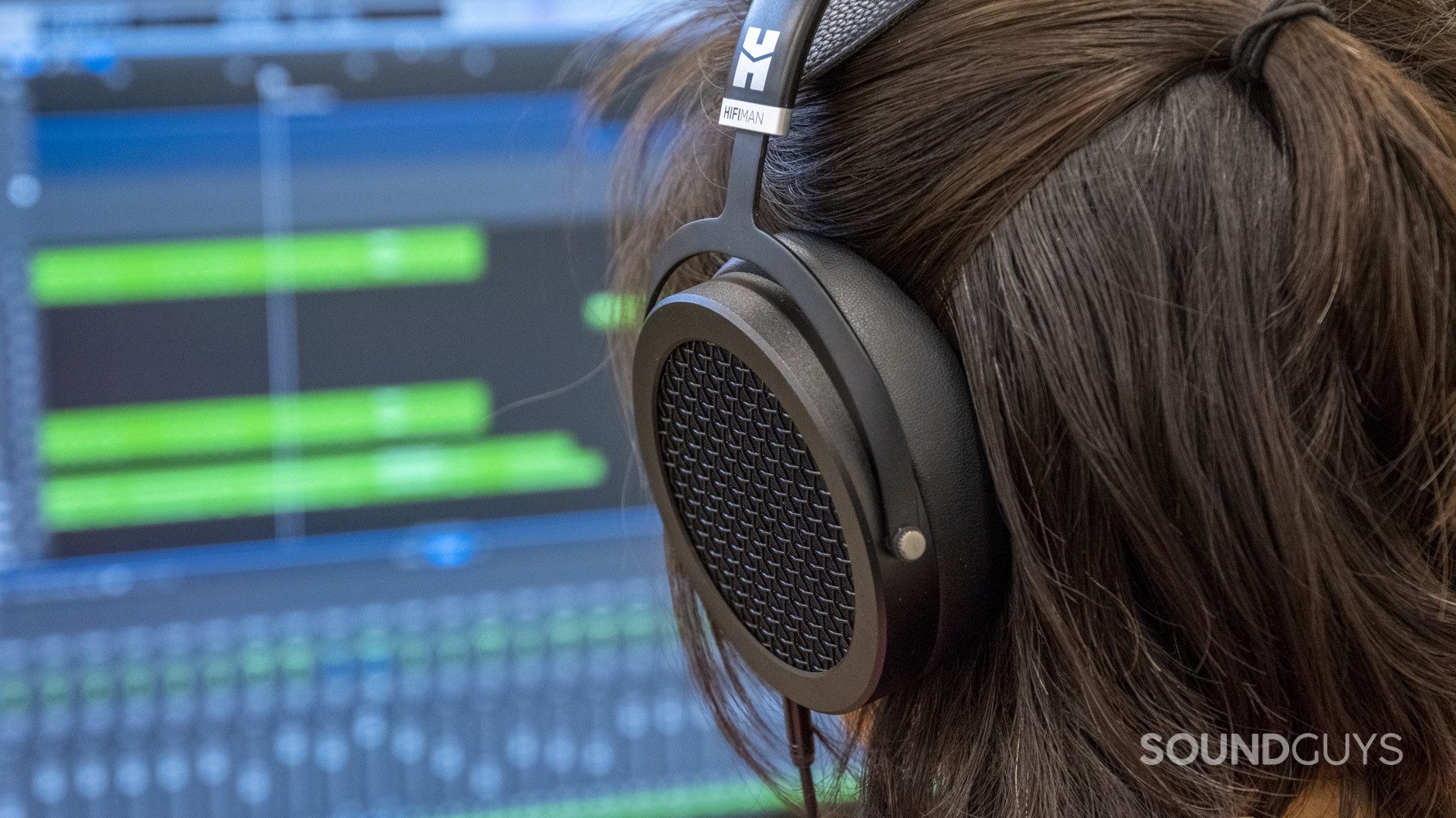 A person wears the HiFiMan Sundara open-back wired headphones with the left ear cup showing.