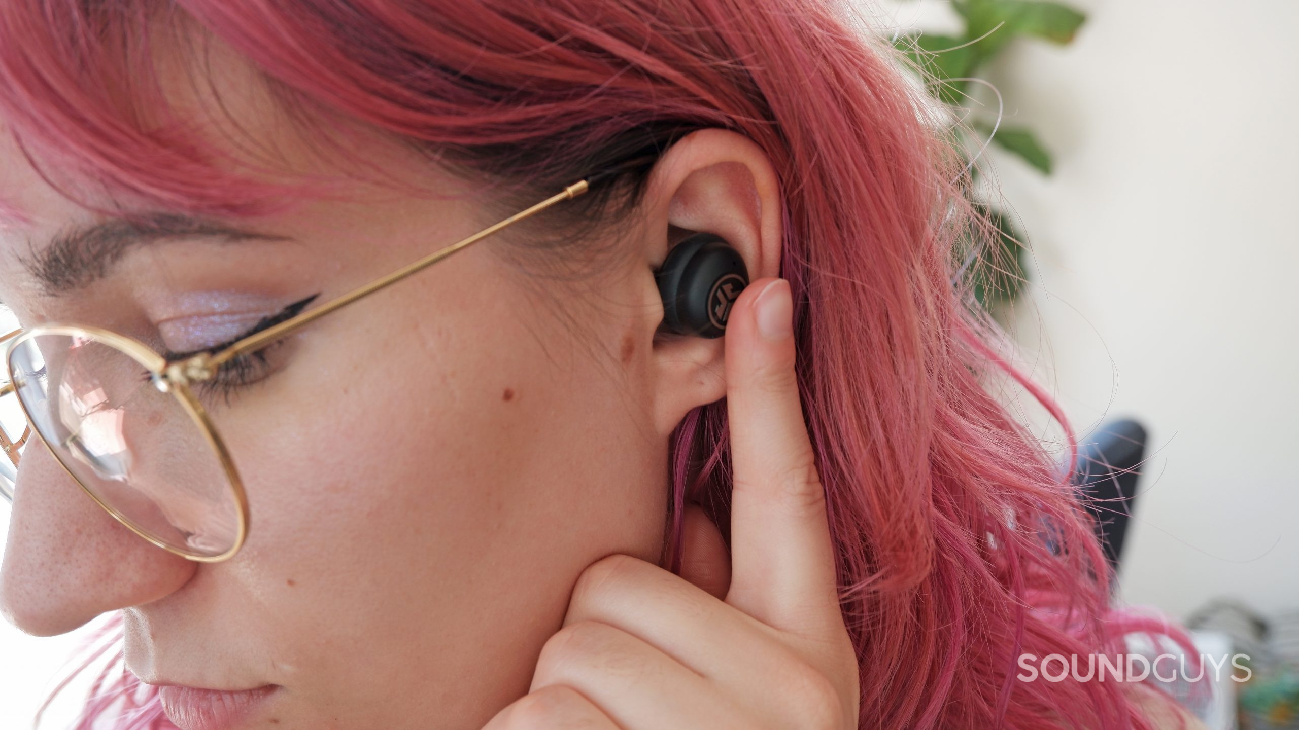 The JLab JBuds Air Pro being worn, with the person touching the earbud touch sensor.
