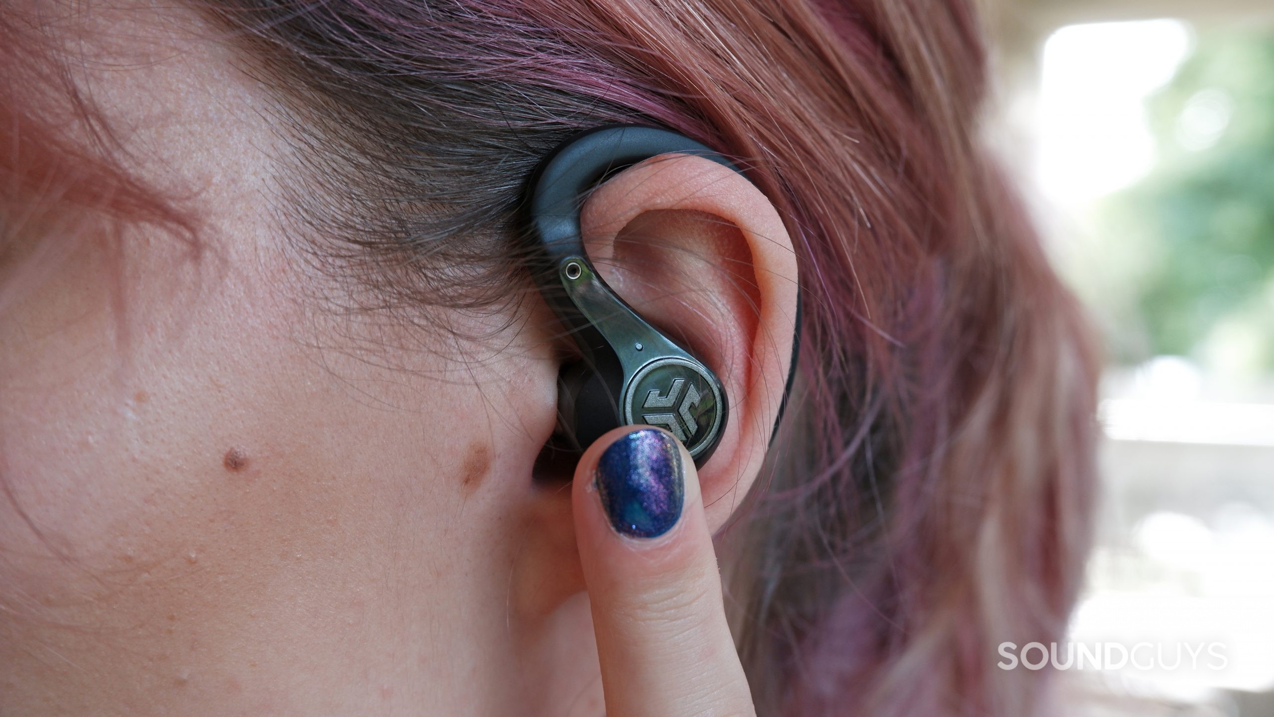 The JLab Epic Air Sport ANC being worn in an ear, with a finger pressing the touch sensor.