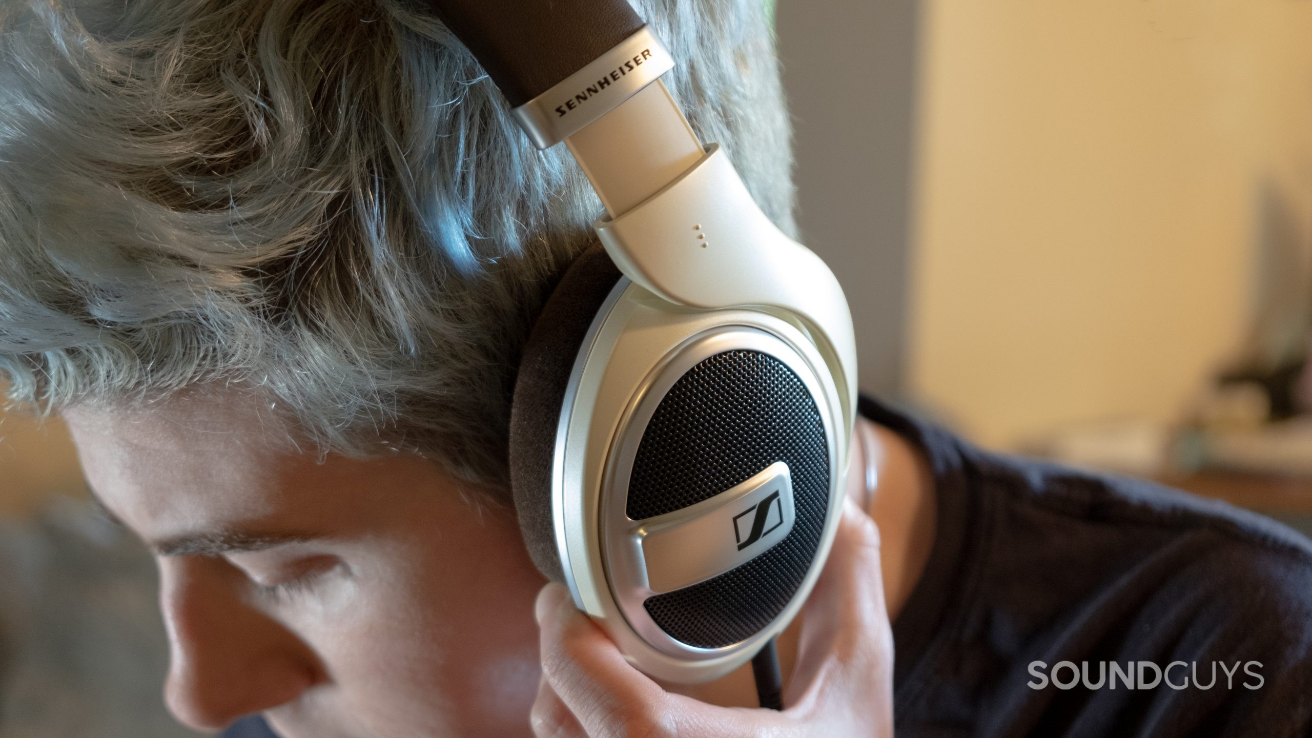 A close up of a man wearing the Sennheiser HD 599 holding the ear cup.