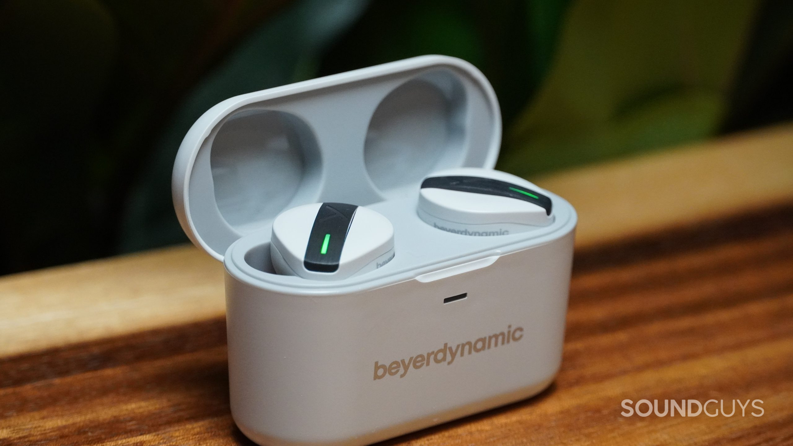 Beyerdynamic Free BYRD earbuds in charging case on a wood table