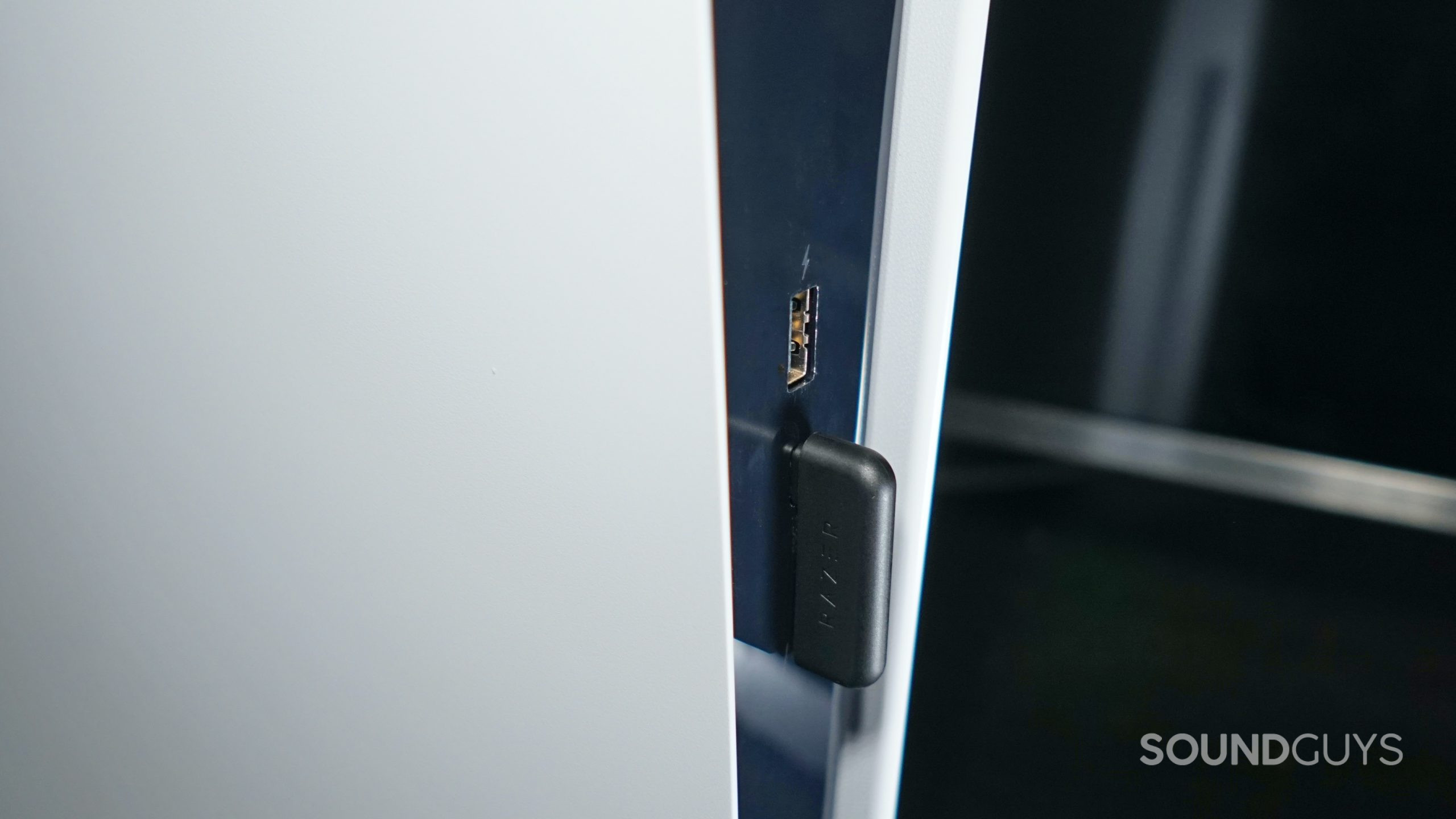 The Razer Barracuda USB-C dongle is plugged into the front port of a PlayStation 5.