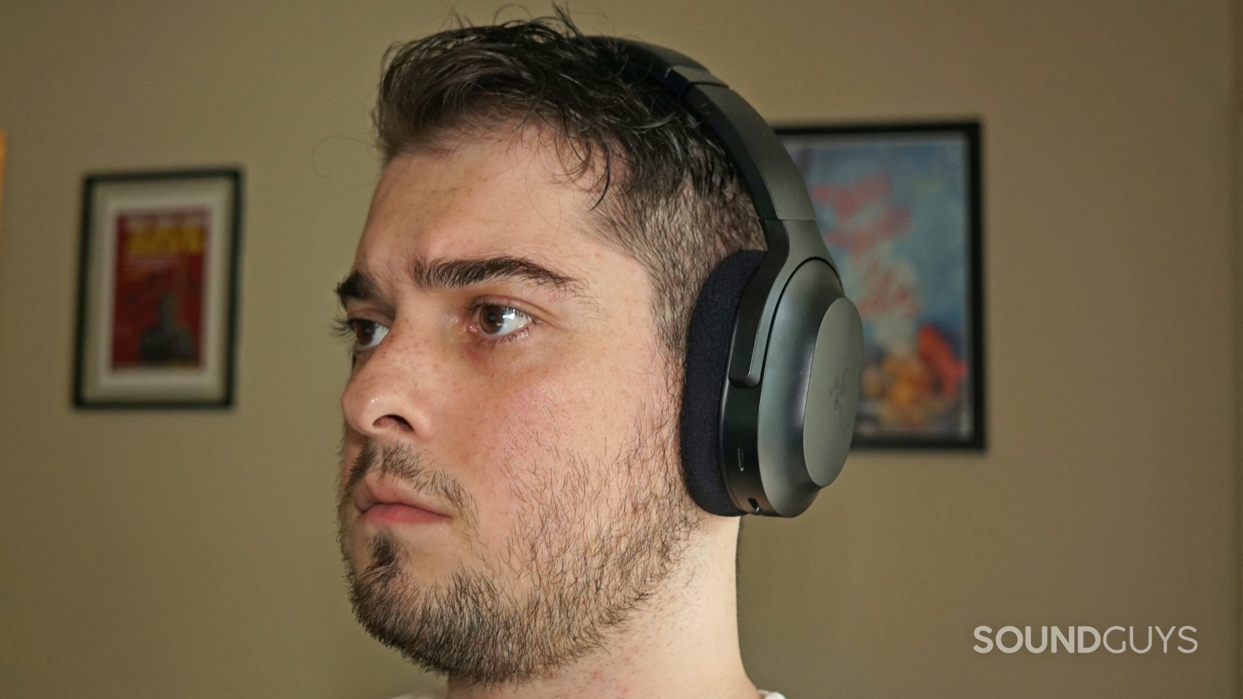 A man wears the Razer Barracuda gaming headset with a poster for My Brother, My Brother, and Me.