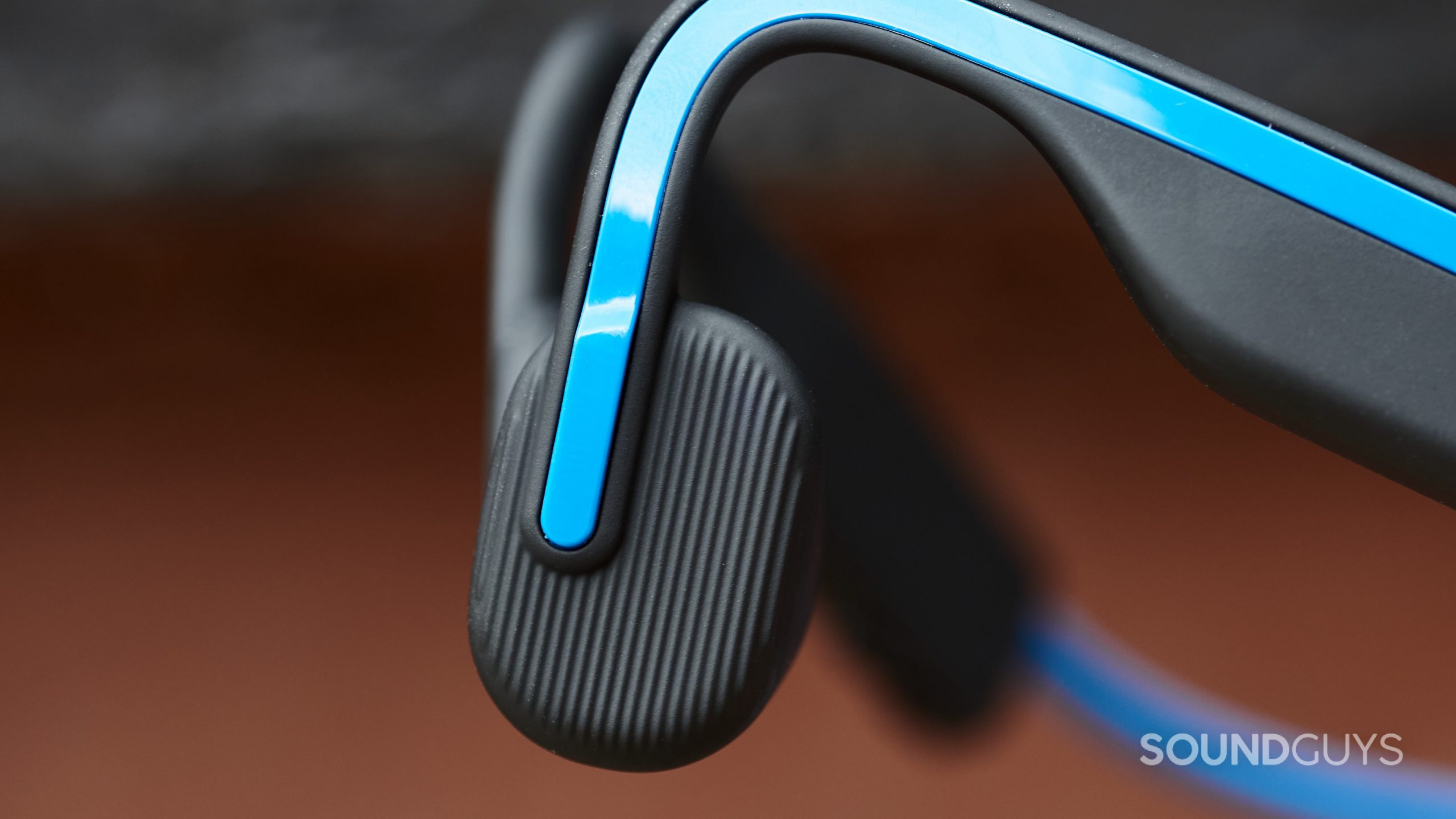 A close-up of the Shokz OpenMove bone conduction headphones' multi-function button on the left ear piece.