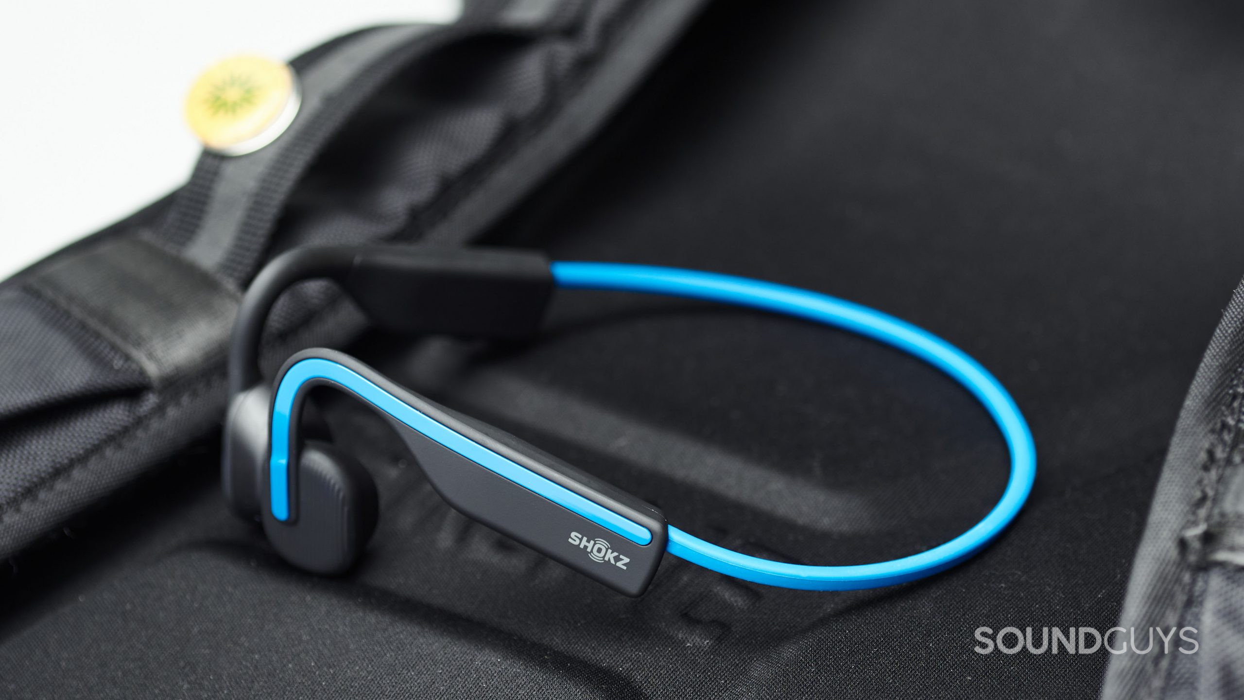 The Shokz OpenMove bone conduction headphones on a backpack.
