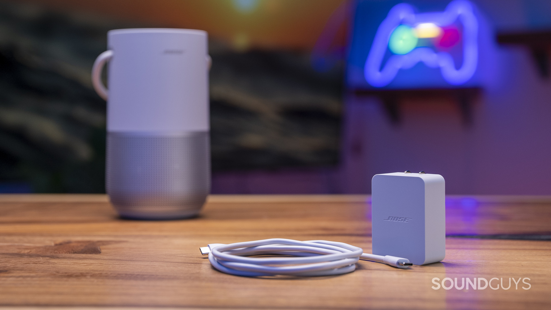 A photo of a Bose Portable Smart Speaker to the left with the included charger and cable to the right.