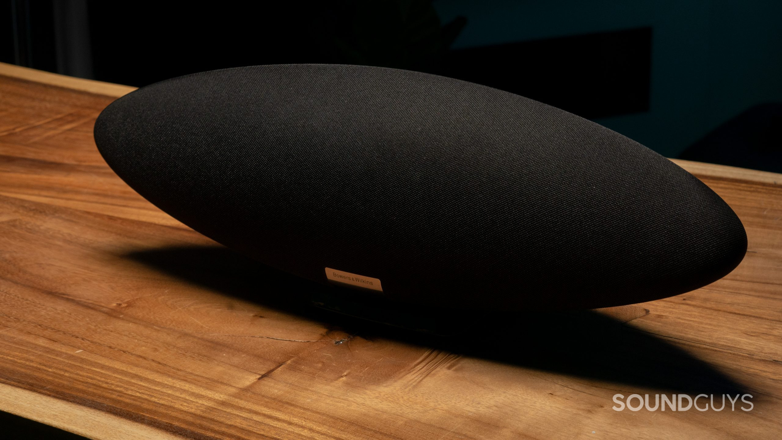 A black Bowers &amp; Wilkins Zeppelin speaker shown at an angle fron the front on a wooden table.
