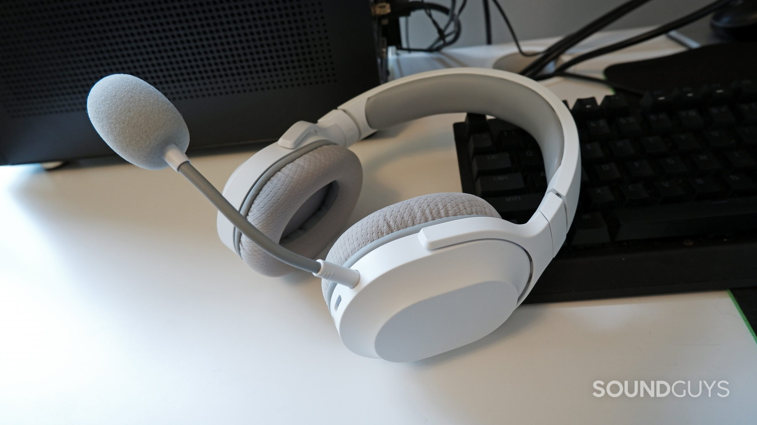 The Razer Barracuda X (2022) laying against a Razer keyboard on a white desk.