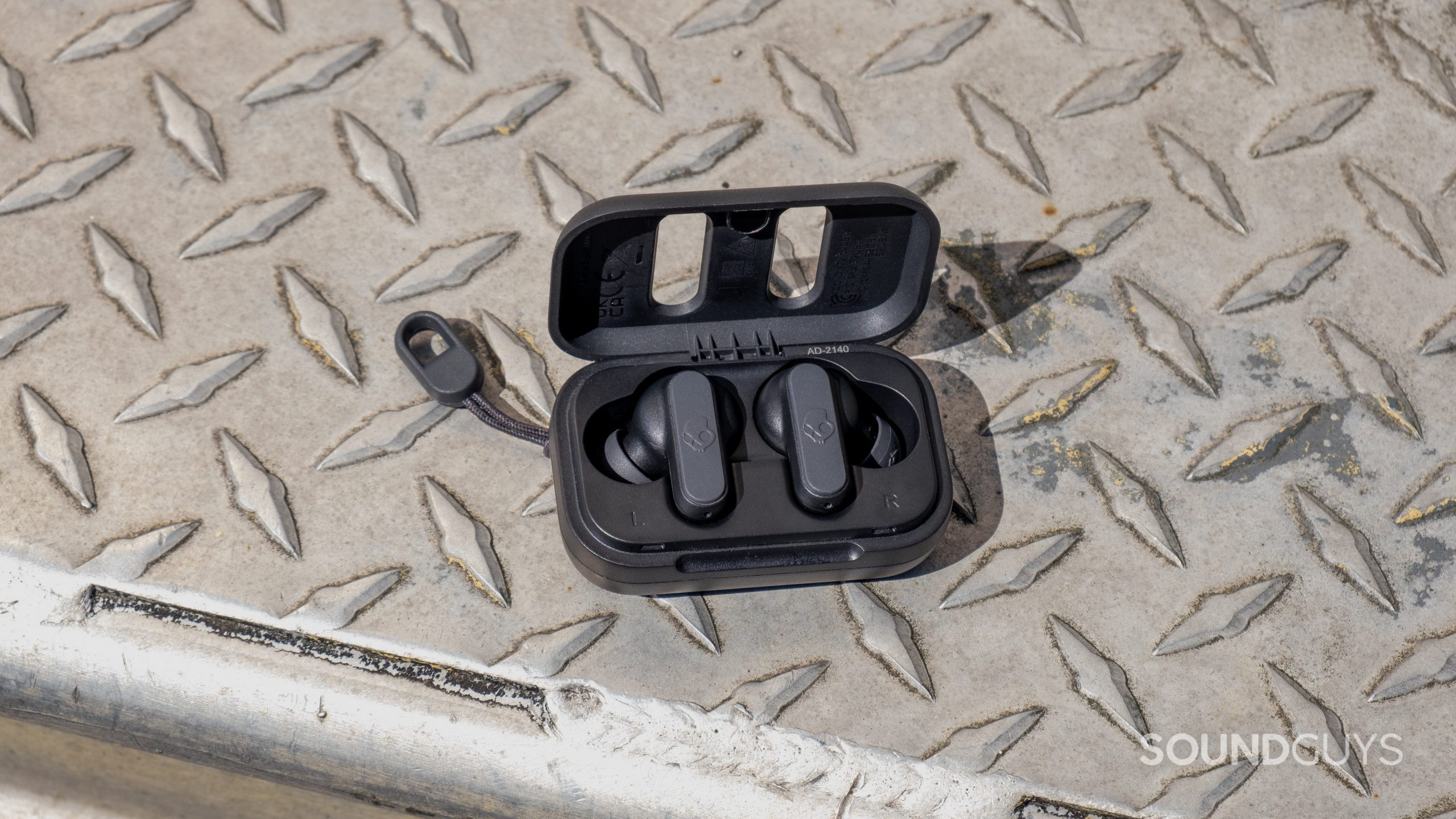 The Skullcandy Dime 2 rests with the open case on a weather worn metal surface.