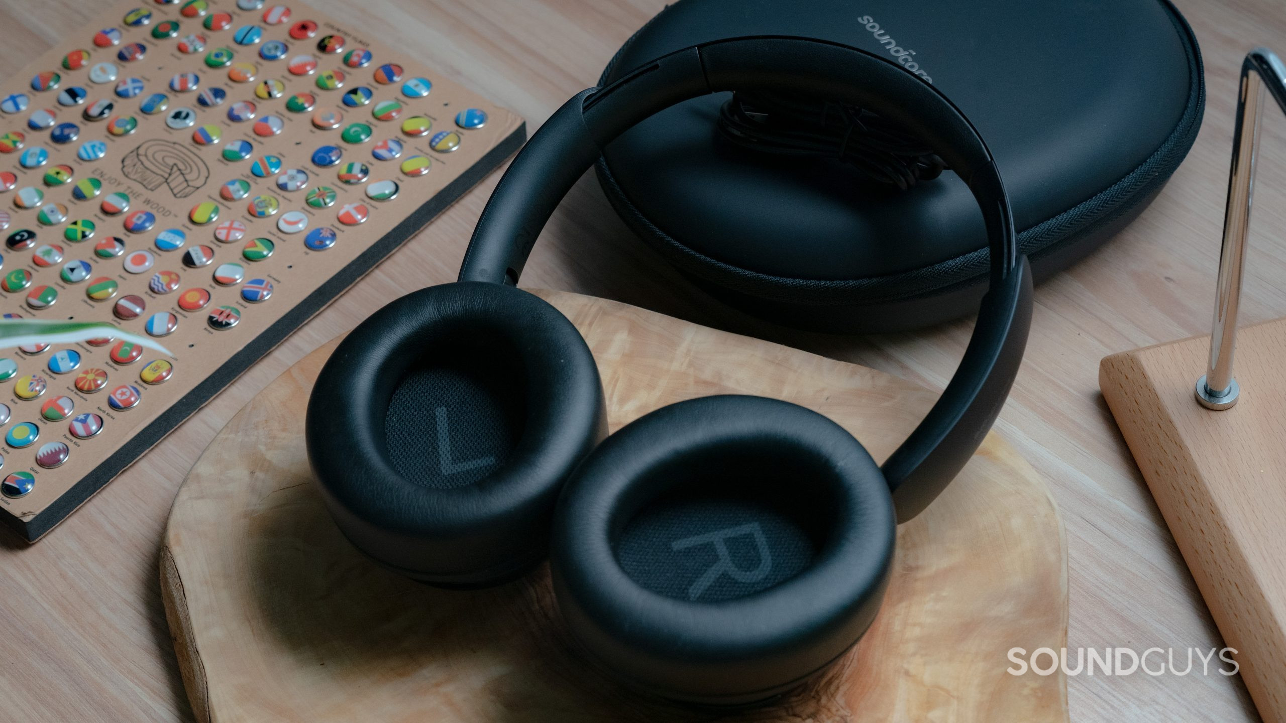The Anker Soundcore Space Q45 sitting on a wooden table with the case in the background, the interior of the ear cups are facing the user.