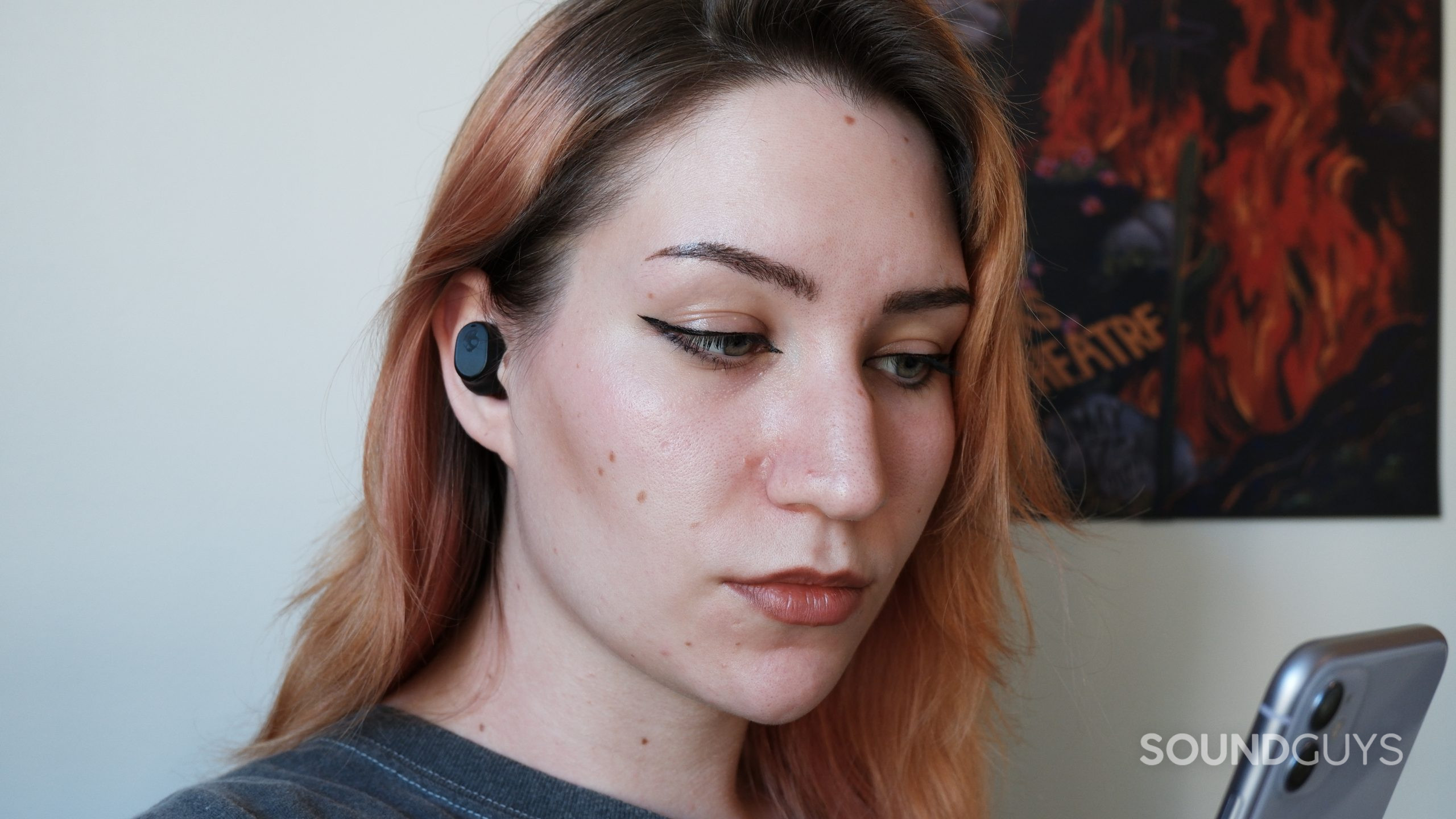 The Skullcandy Mod XT being worn by a person while they hold a phone.