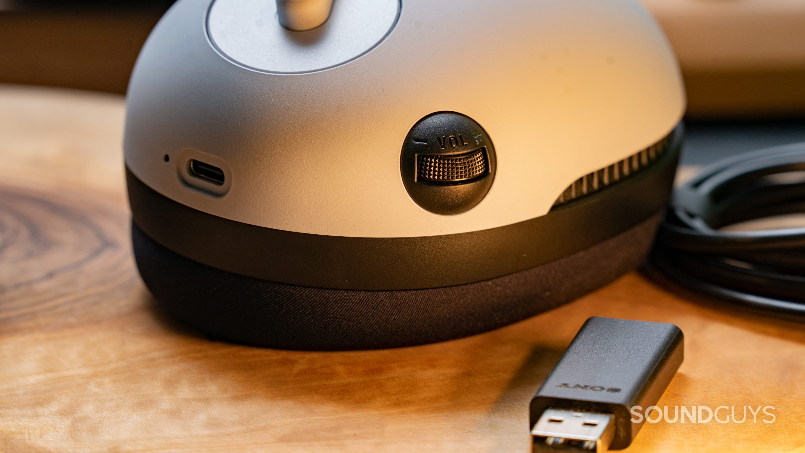 A close up of the Sony INZONE H7 gaming headset's volume dial, with the USB dongle in the forground.