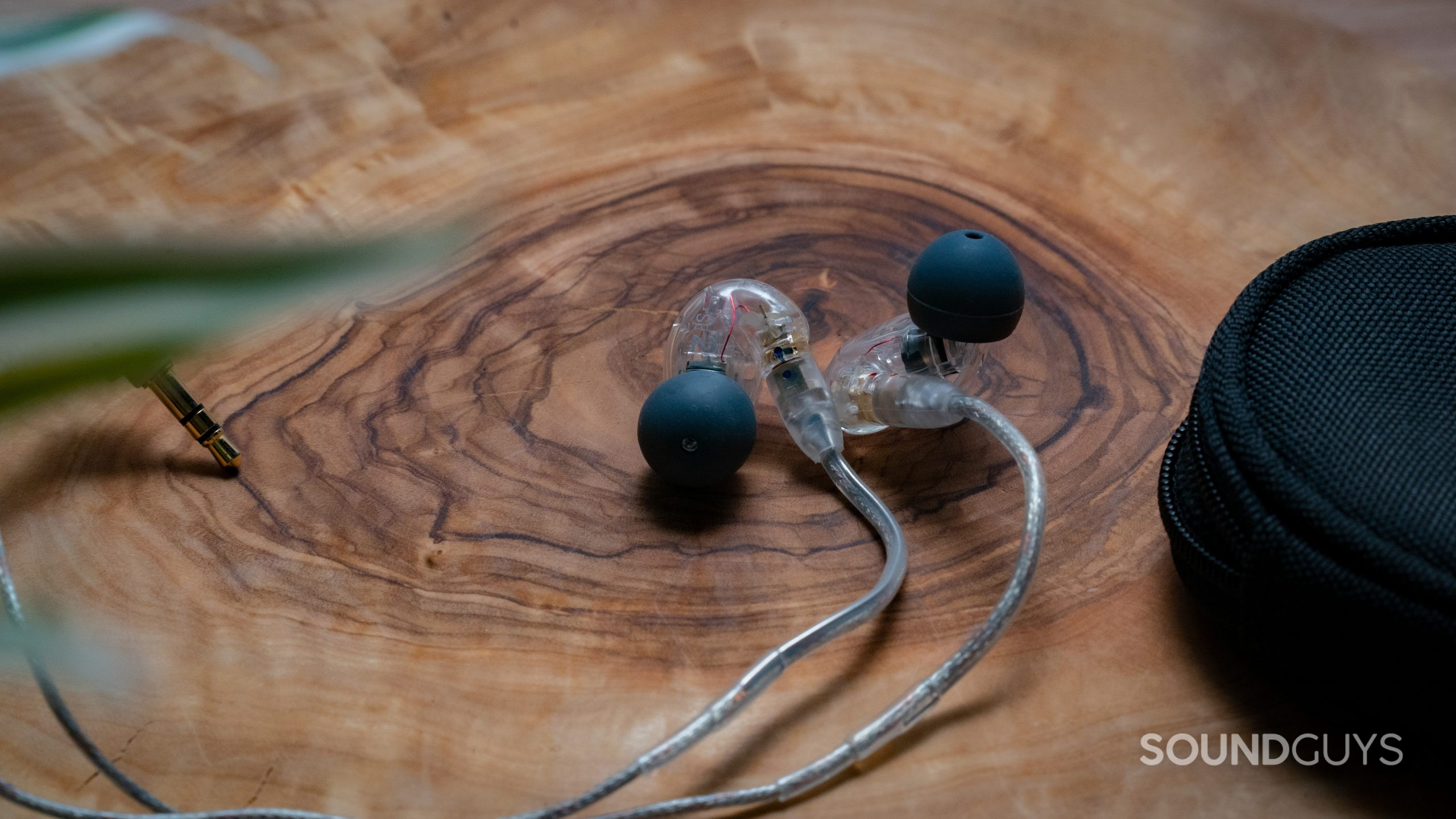 The Shure SE215 rests on a wood surface.