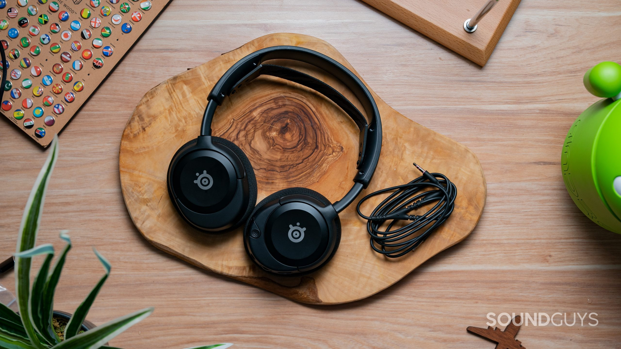 The SteelSeries Arctis Nova 1 sitting on a wooden tabletop surrounded by knicknacks.