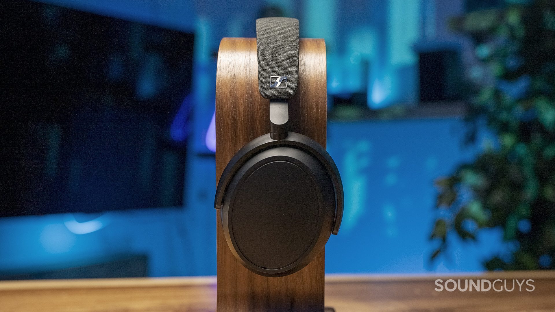 A profile view of the Sennheiser MOMENTUM 4 Wireless headphones on an omega-shaped headphone stand.