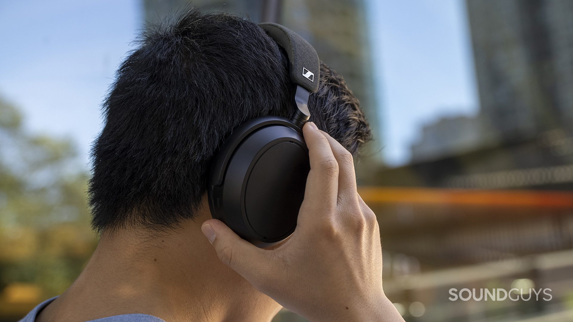 A man wears the Sennheiser Momentum 4 Wireless outdoors.