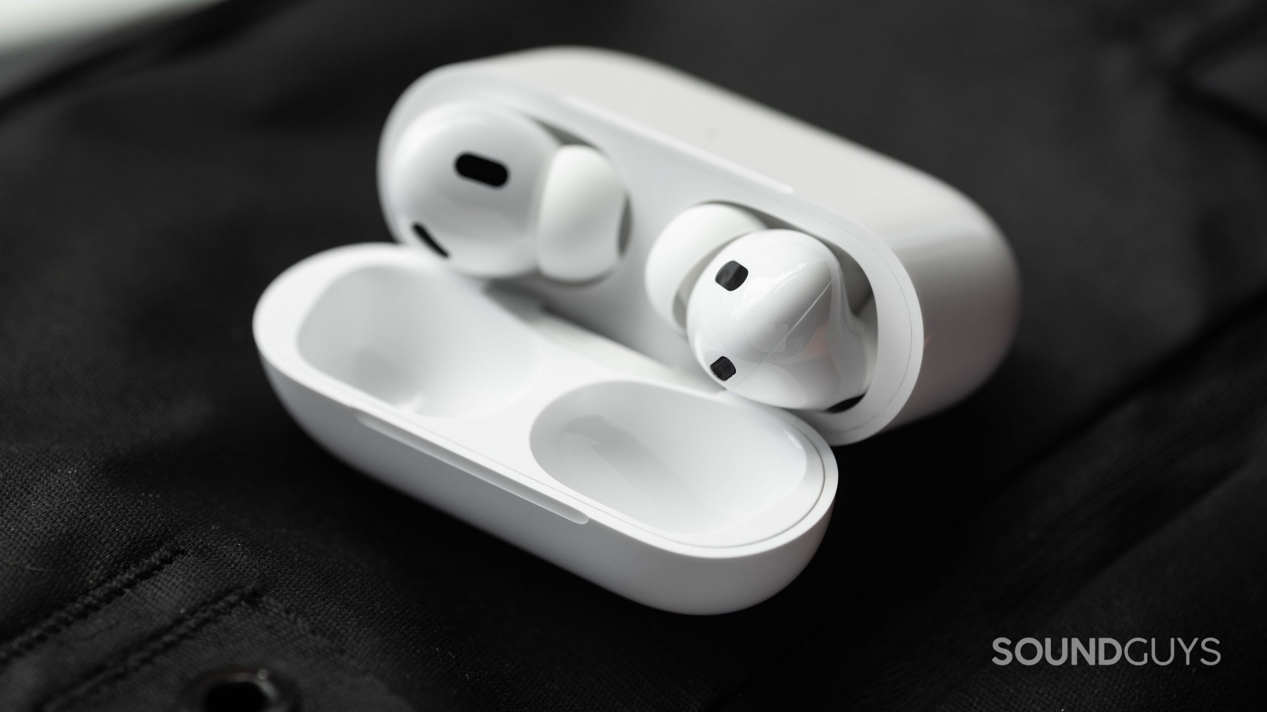 The Apple AirPods Pro (2nd generation) case is open and laying at an angle to show the earbuds and their sensors.