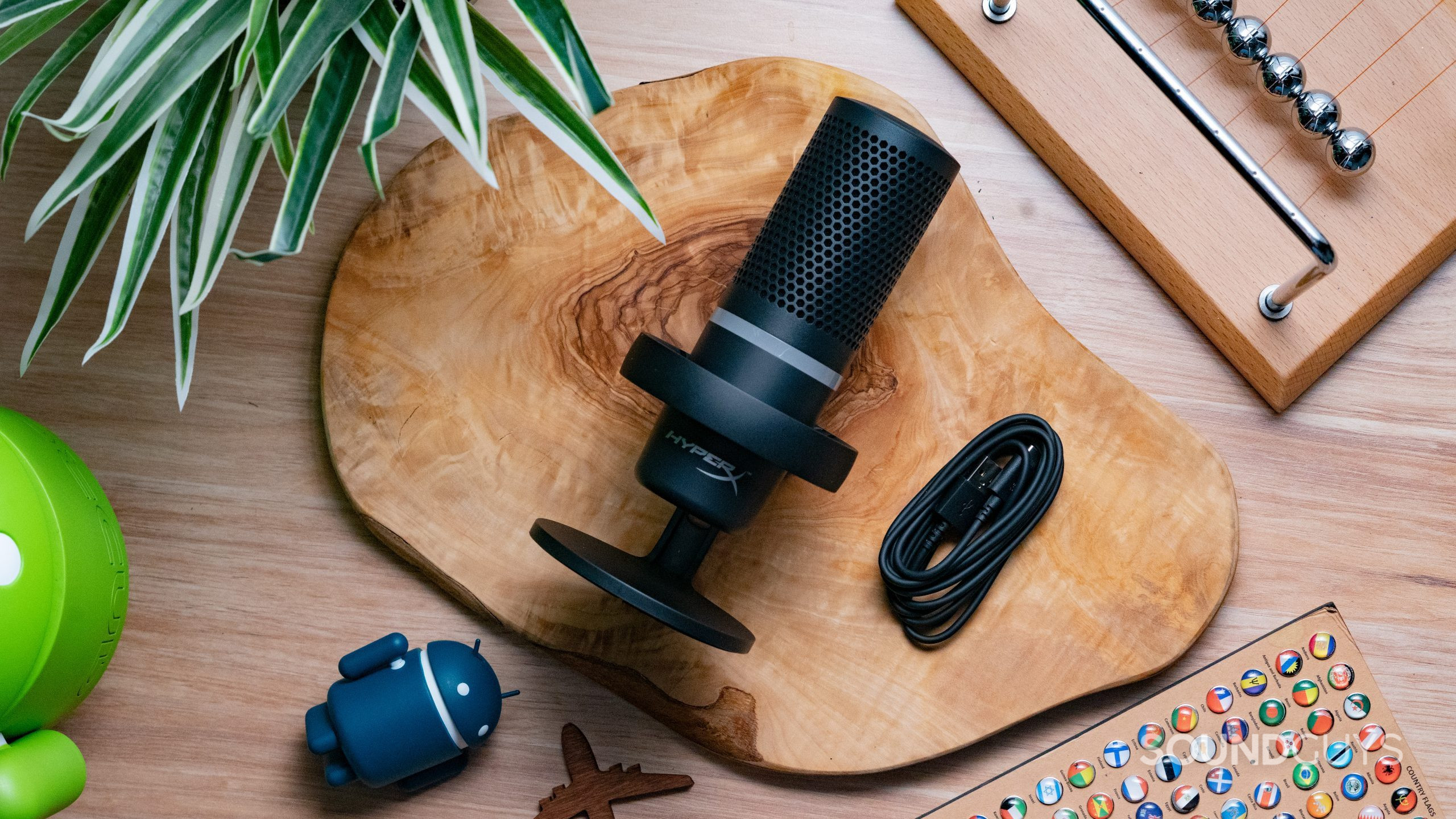 The HyperX DuoCast sitting on a wooden table with its USB-C cable to the right of it.