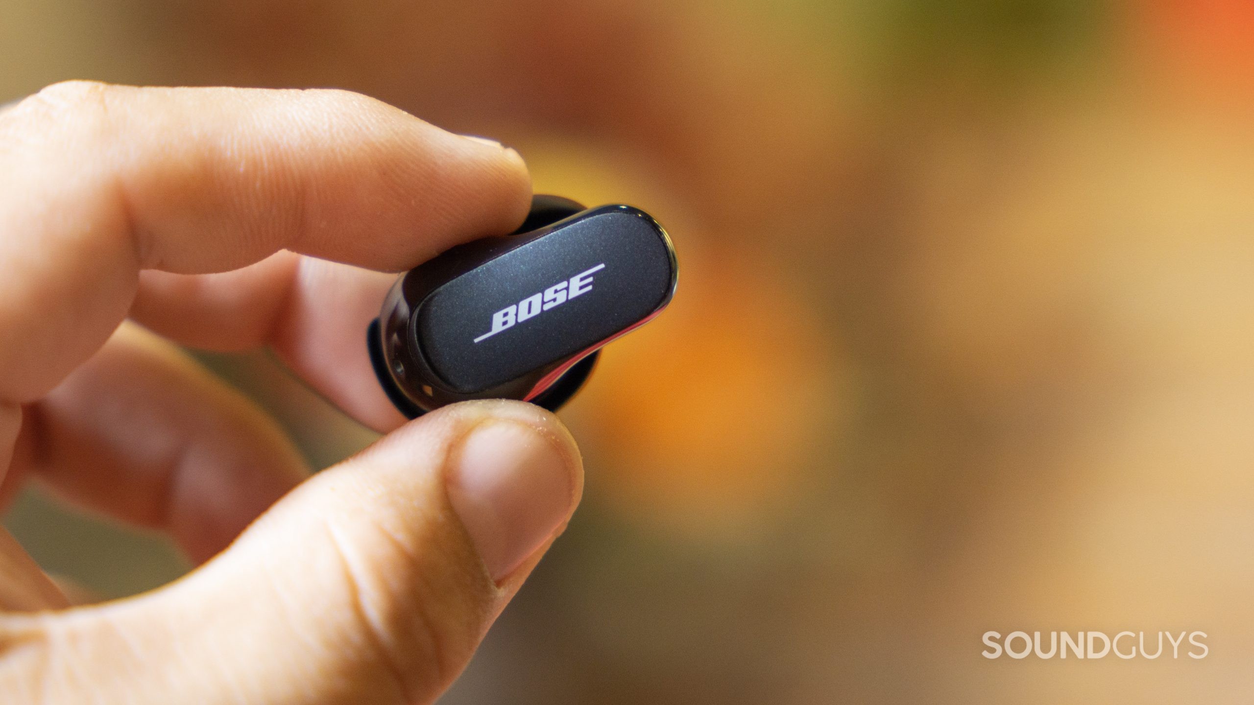 A hand holds the Bose QuietComfort Earbuds II.