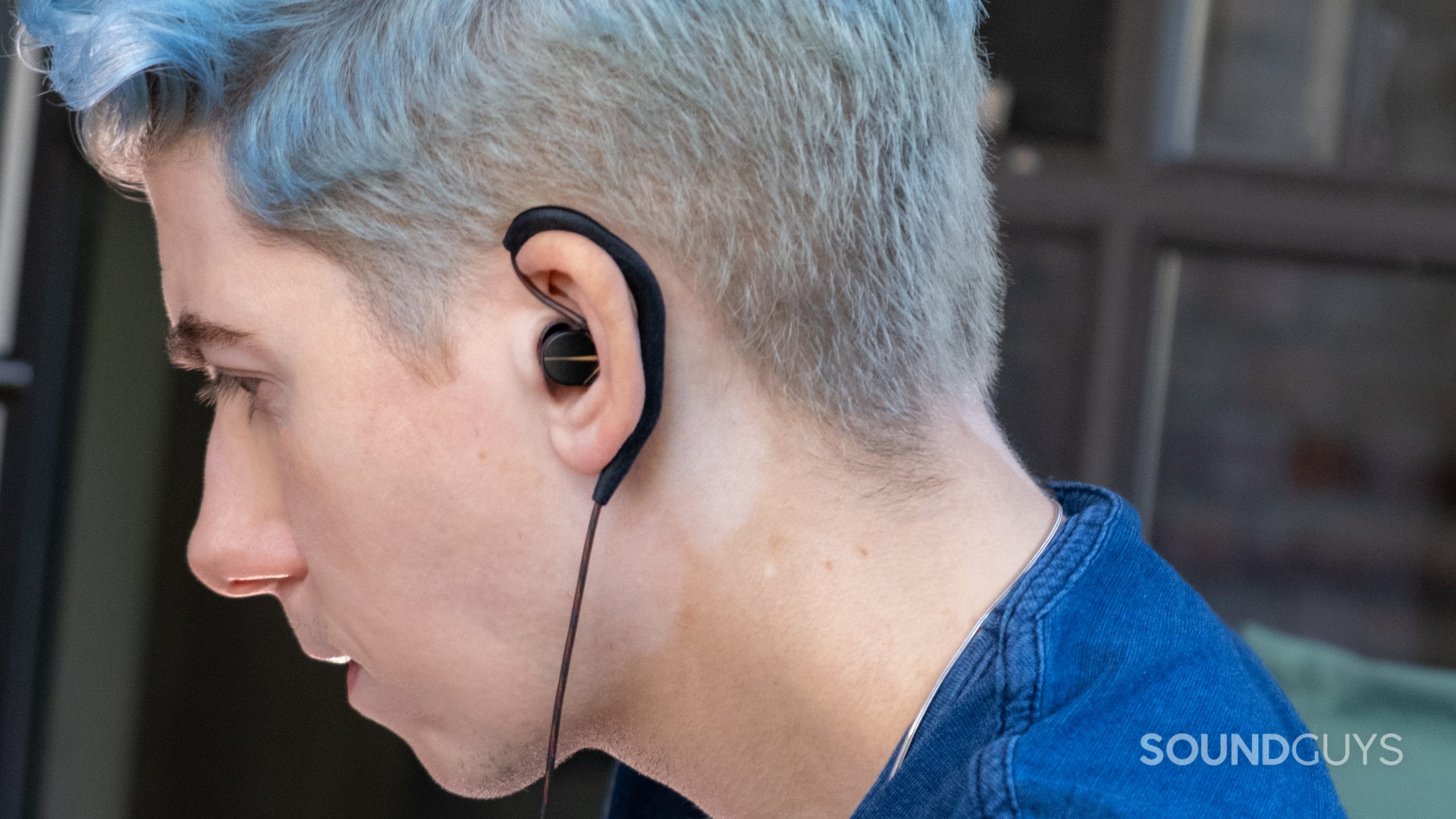 A man with blue hair wear the Moondrop Chu, showing the wrap around cabling.