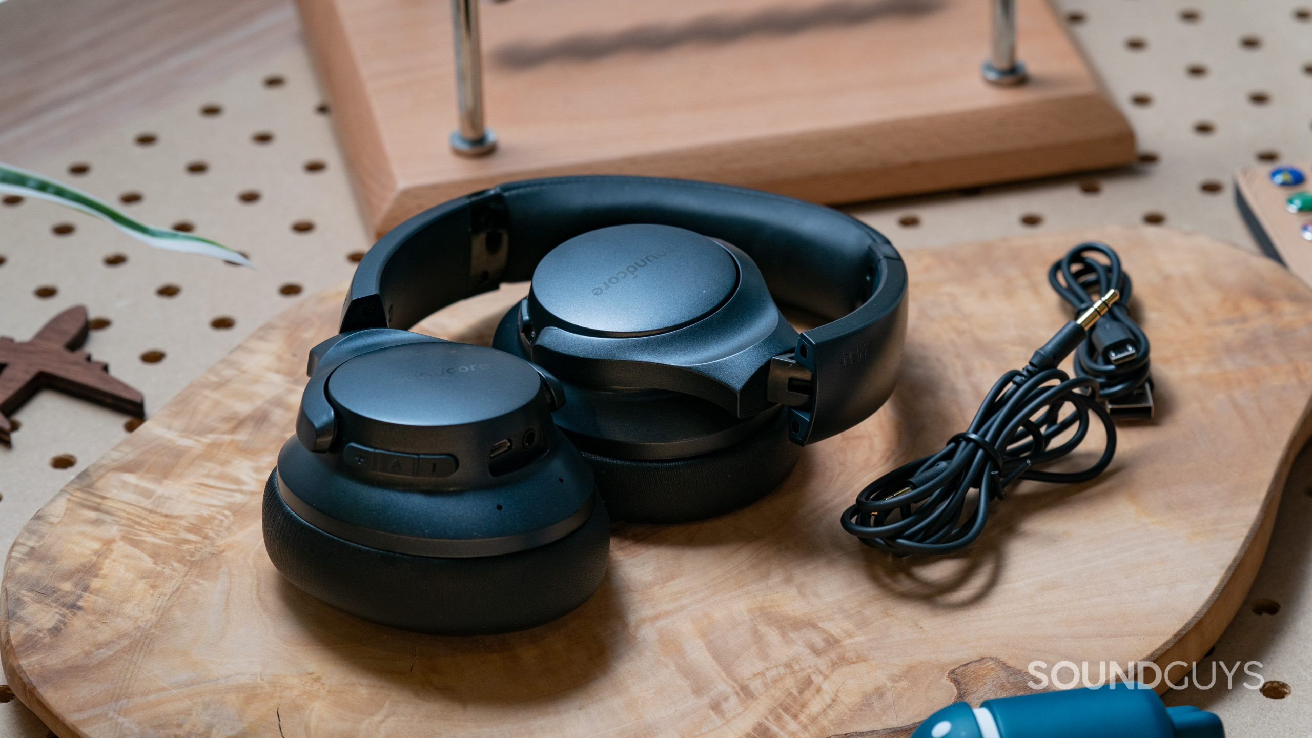 The Anker Soundcore Life Q20 headphones folded up on a wood surface next to the charging cable.