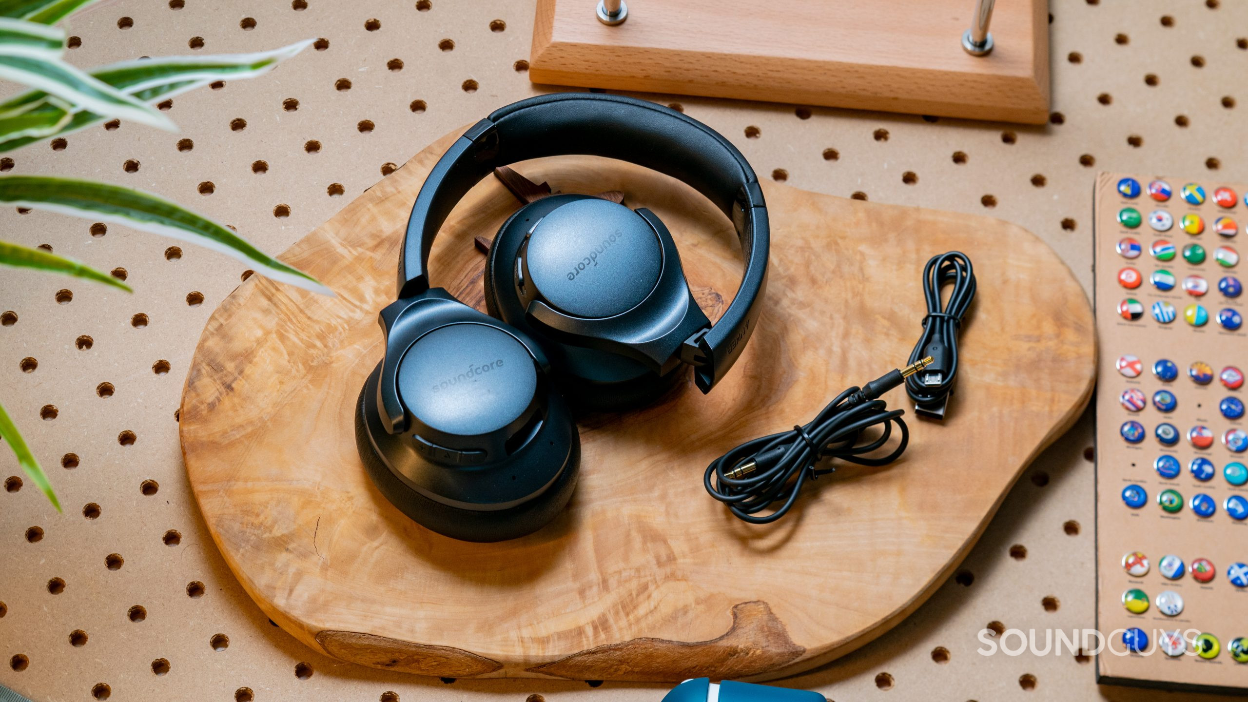 The Anker Soundcore Life Q20 wireless noise canceling headphones folded up on a wooden surface next to the included cables.