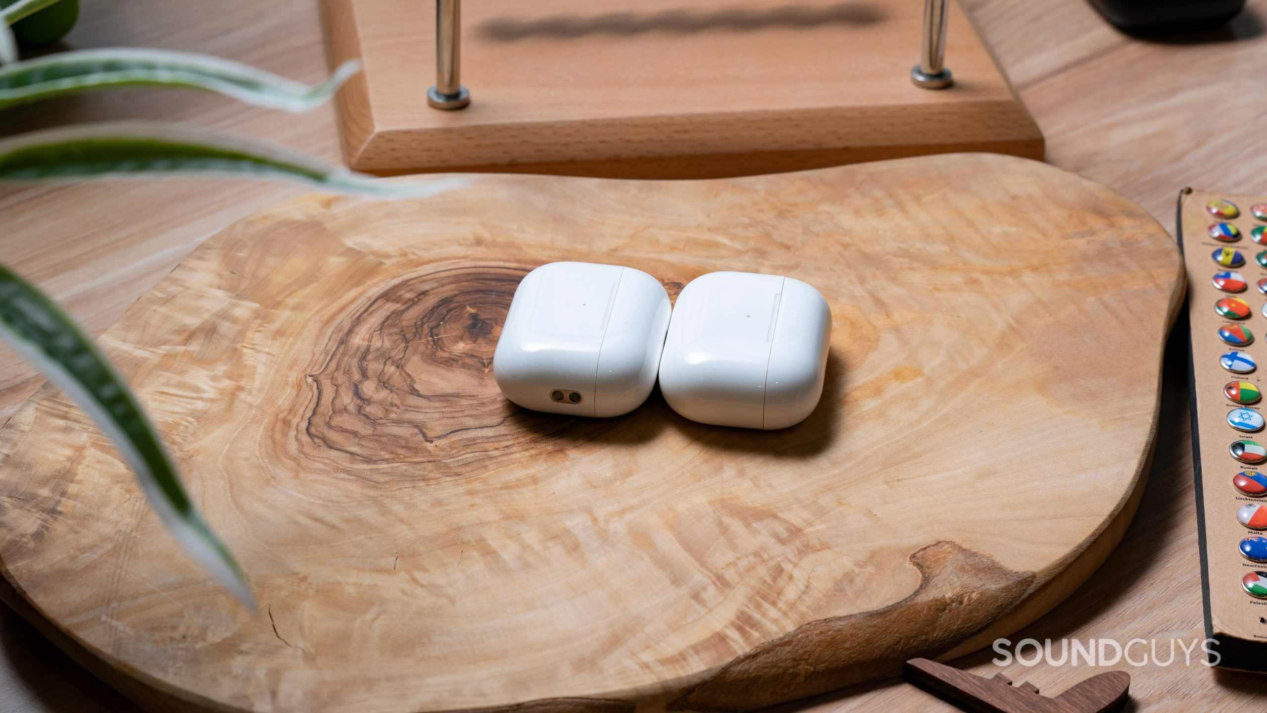 The Apple AirPods Pro (2nd generation) case lays on a wooden surface next to the Apple AirPods Pro (1st generation) case.
