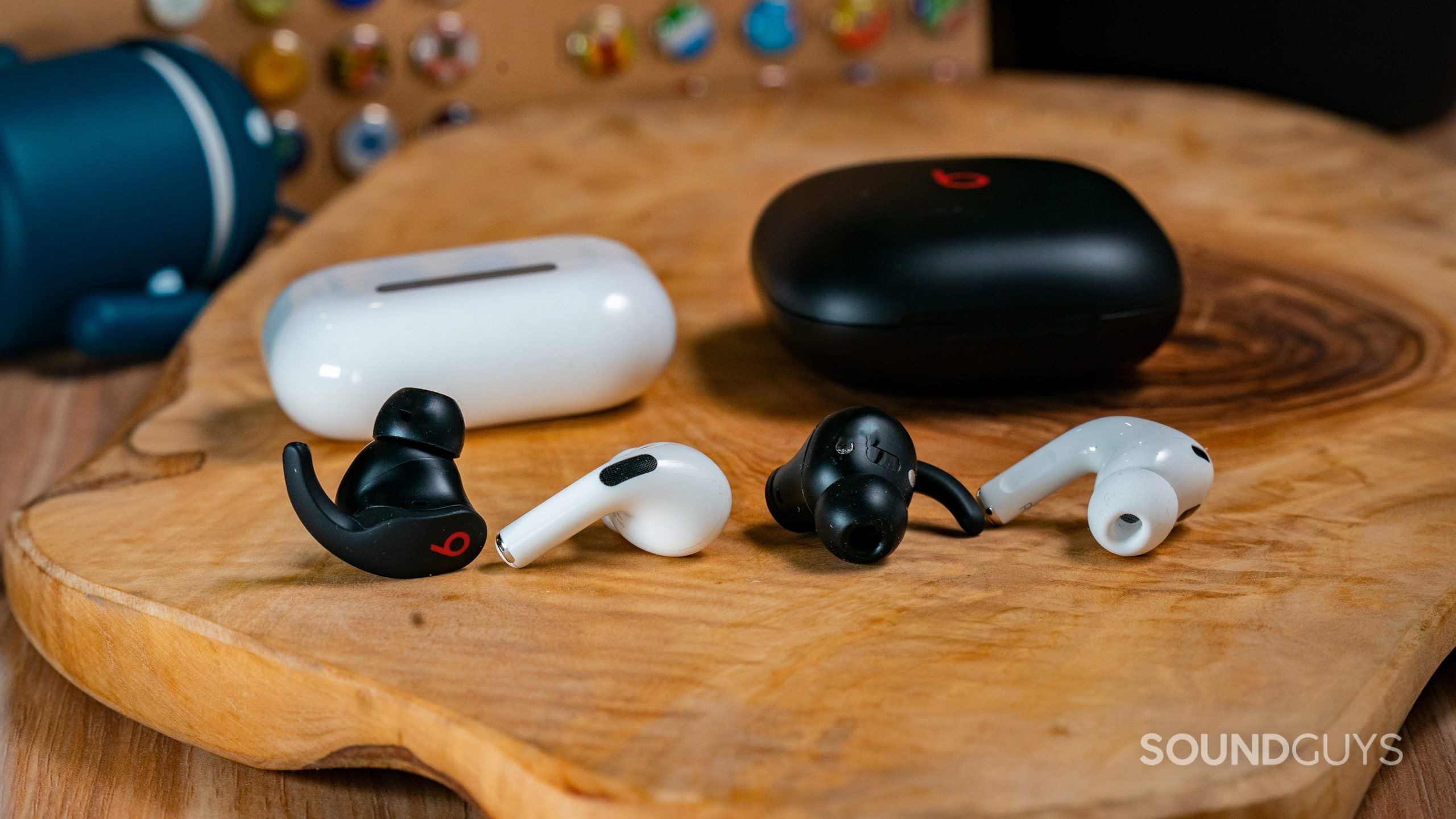 The AirPods Pro (2nd generation) and Beats Fit Pro earbuds and cases next to each other on a wooden surface.