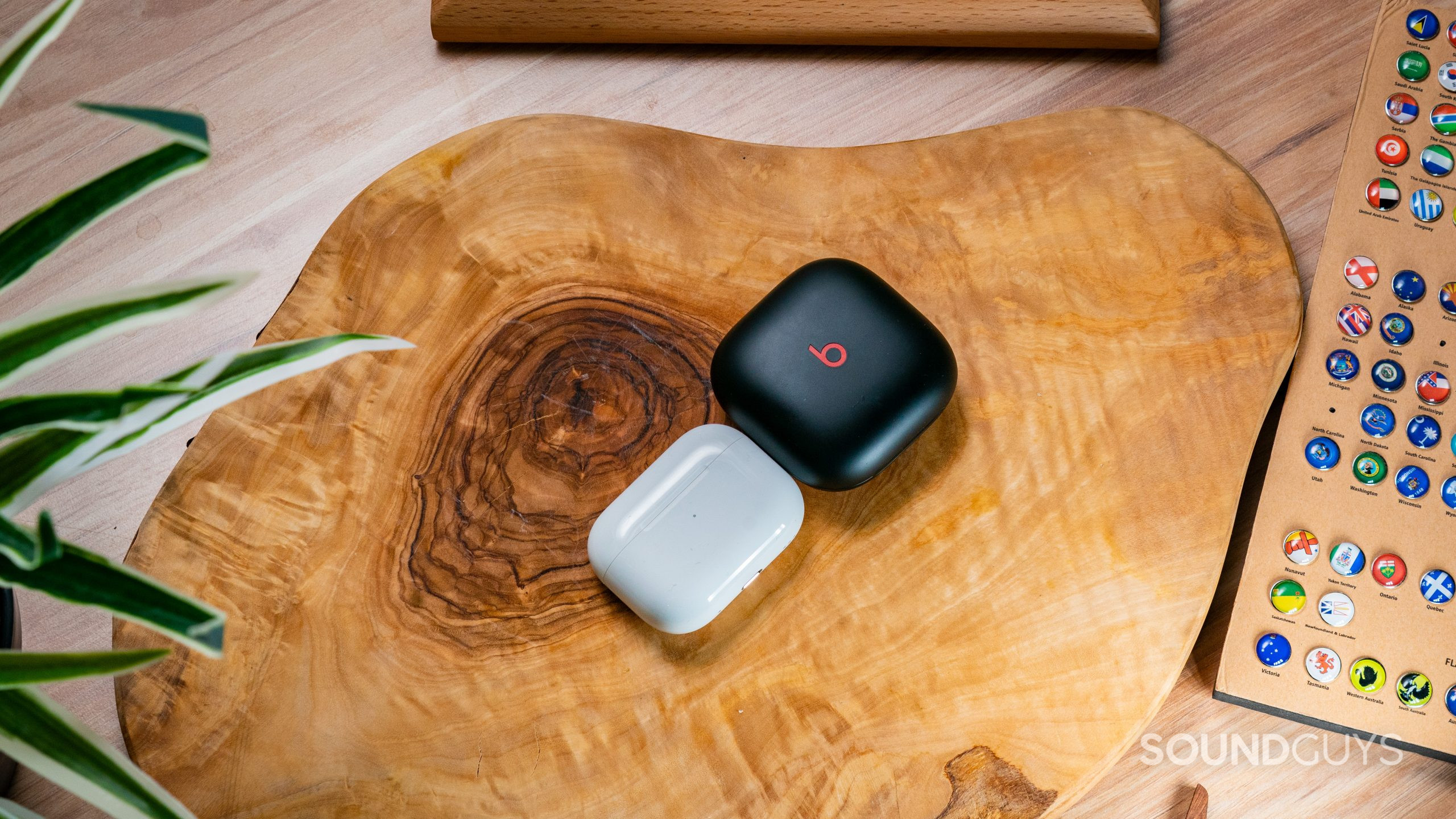 The cases of the AirPods Pro (2nd generation) and Beats Fit Pro beside each other on a wooden surface.