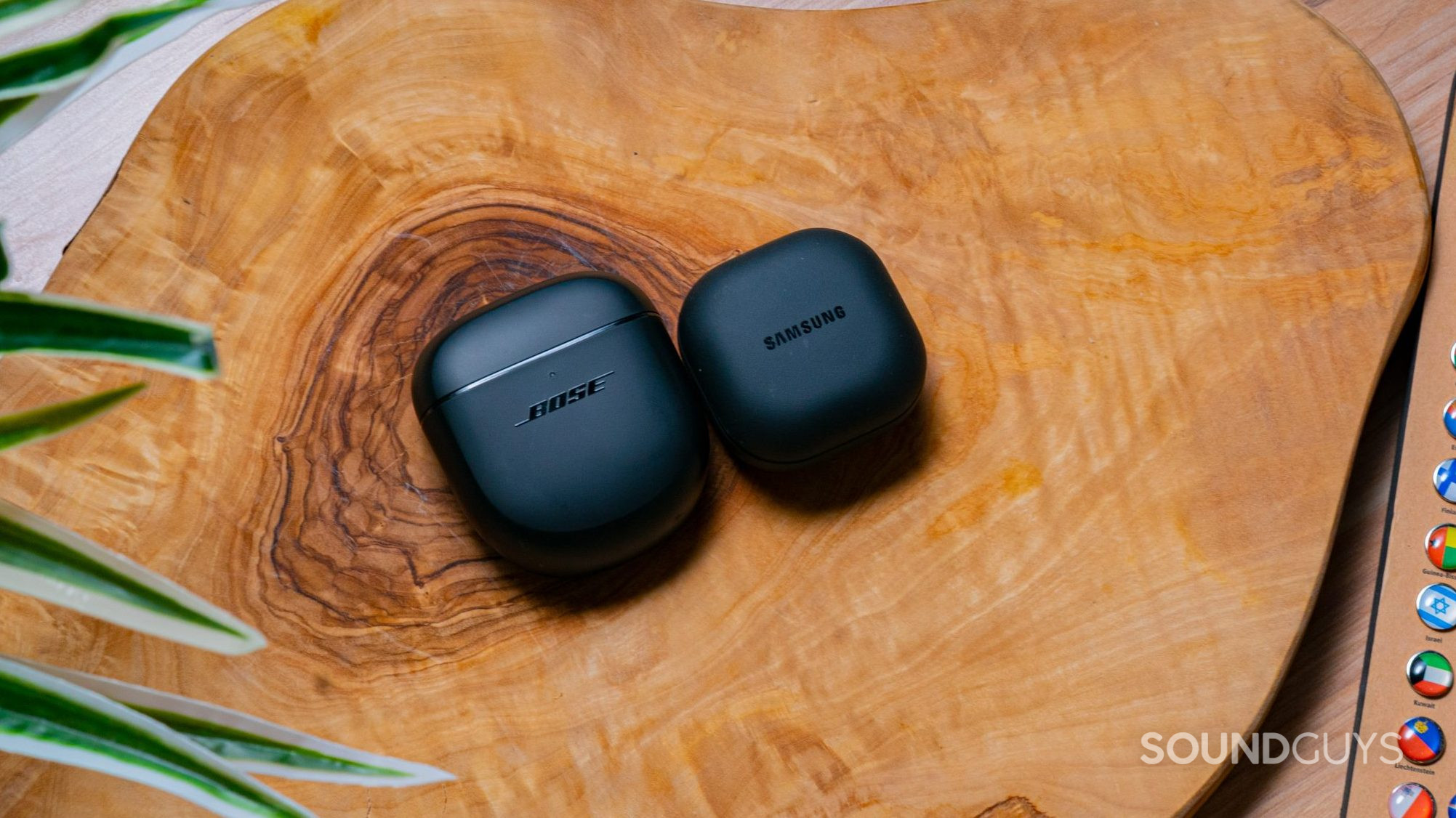 The Bose QuietComfort Earbuds II and Samsung Galaxy Buds 2 Pro cases next to each other on a wooden surface.