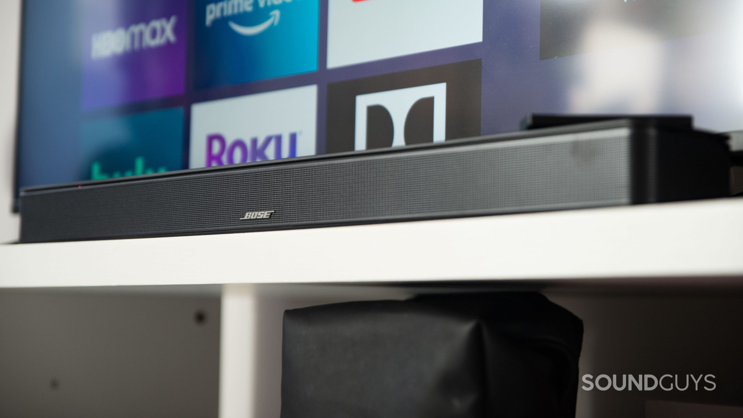 The Bose Smart Soundbar 600 rests on a TV stand beneath a TV.