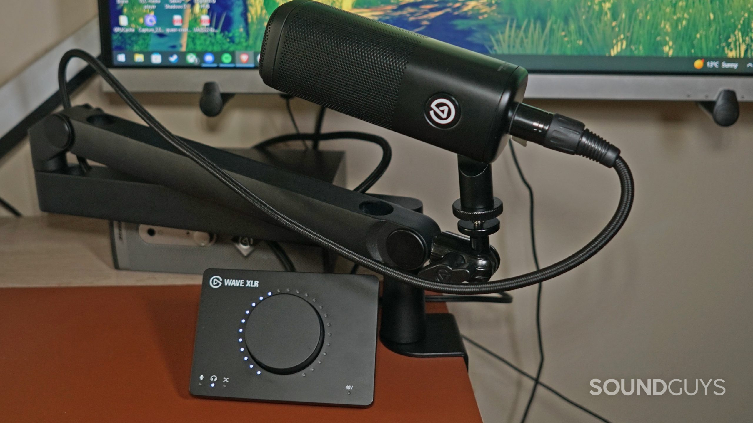 The Elgato Wave DX sits on an Elgato microphone arm above the Elgato Wave XLR audio interface on a desk in front of a Viewsonic computer monitor.