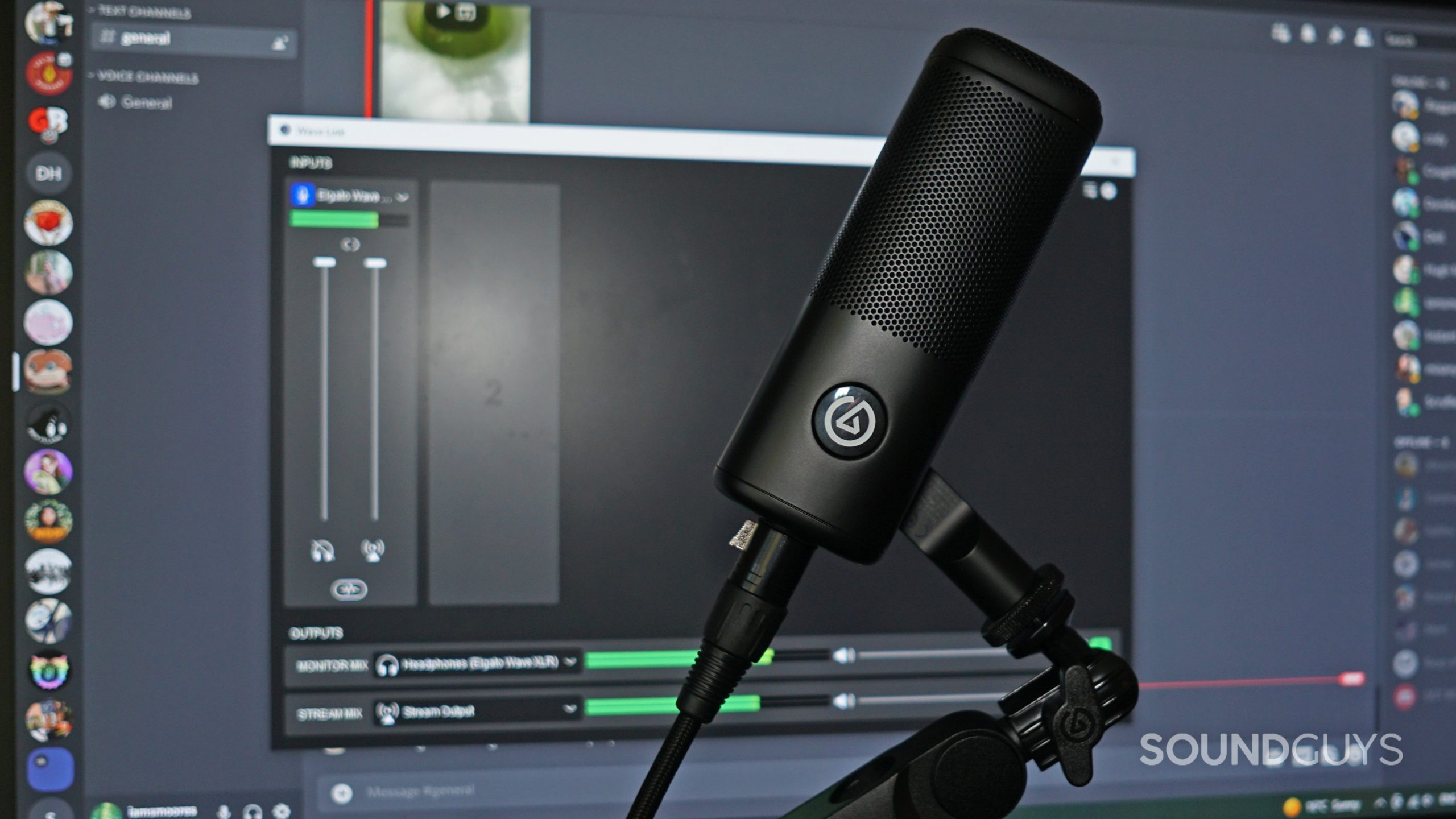 The Elgato Wave DX sits on a microphone arm in front of a viewsonic monitor displaying the Elgato Wave Link app
